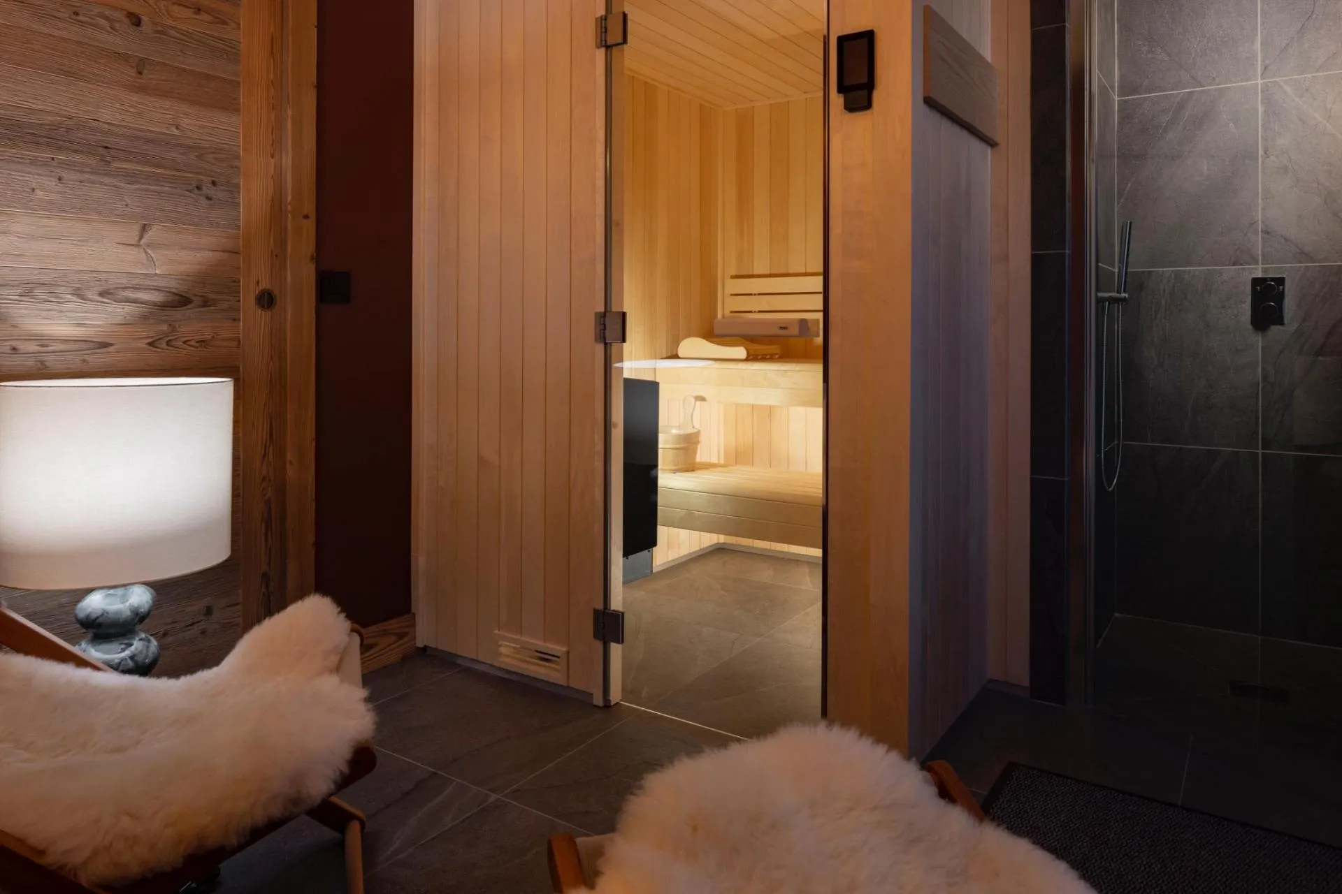 Sauna entrance beside relaxation seating and shower