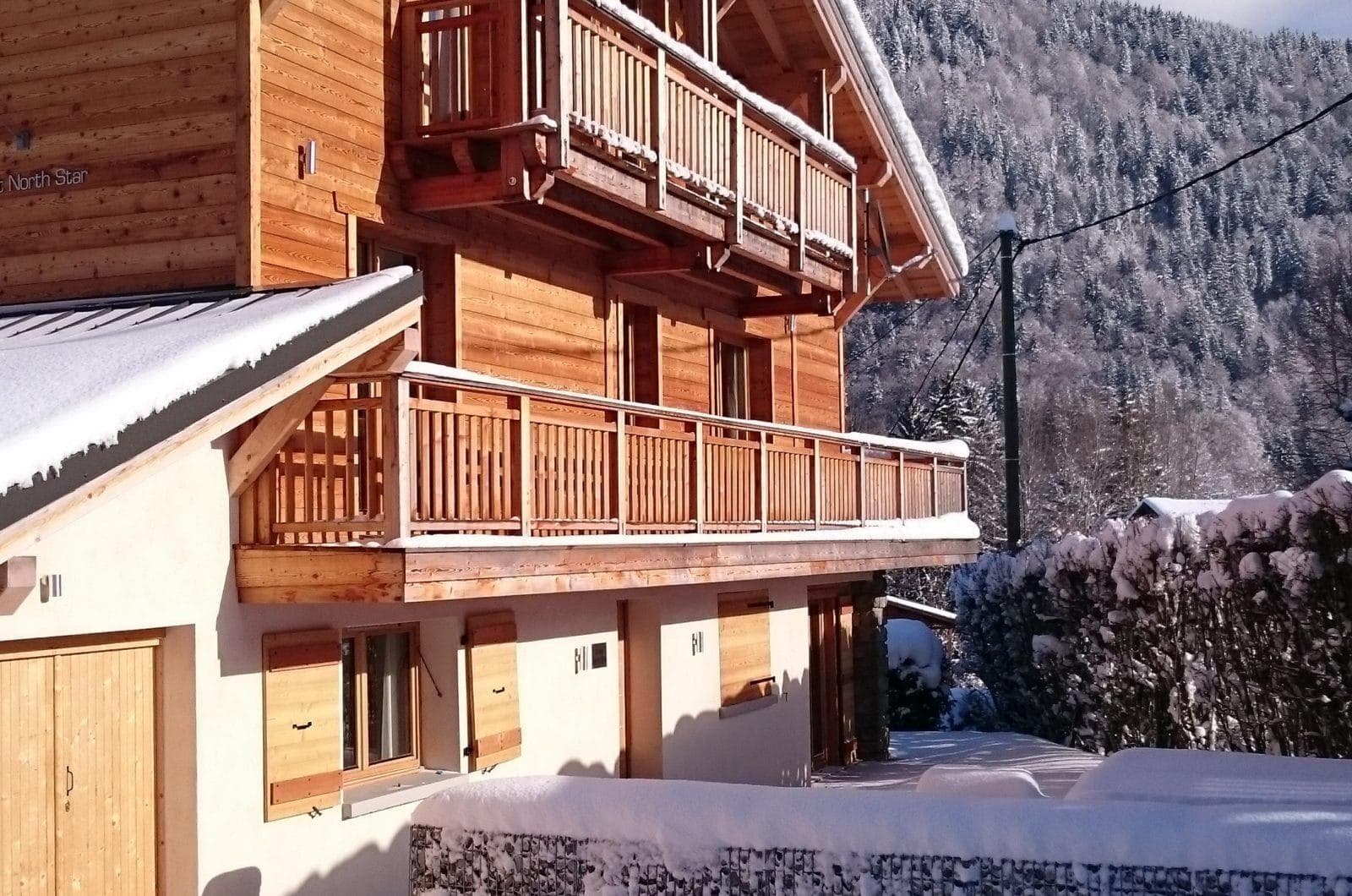 Chalet exterior with multi-level sun balconies and forest backdrop