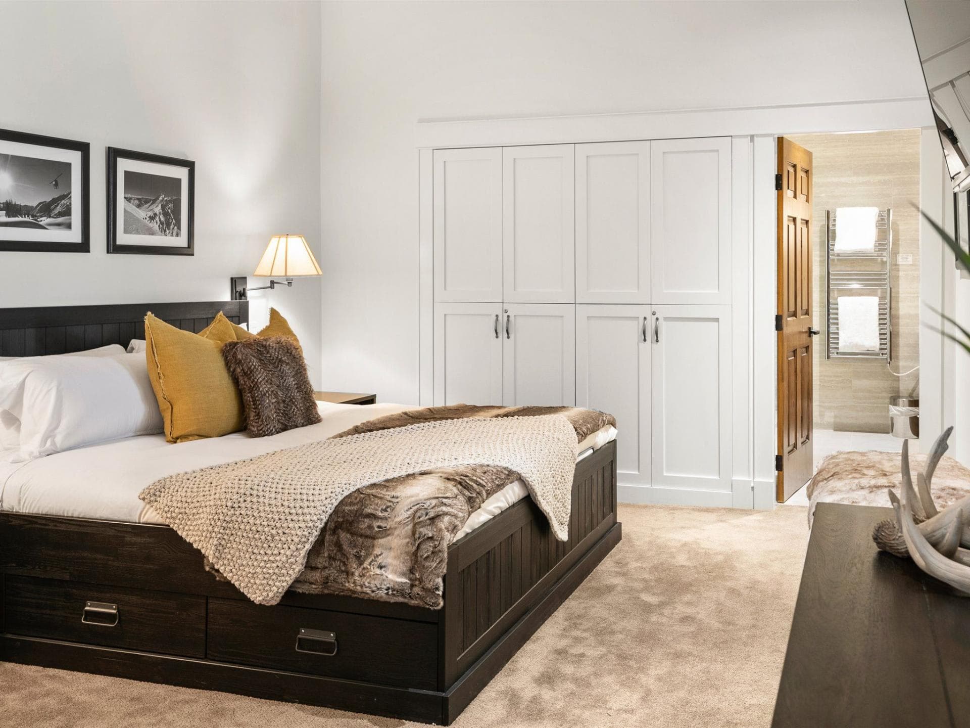 Primary bedroom with ensuite bathroom, king bed, and built-in closet storage