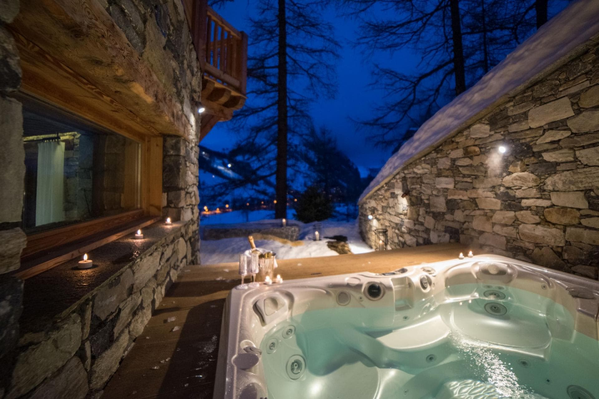 Sunken outdoor hot tub with forest views and stone privacy walls