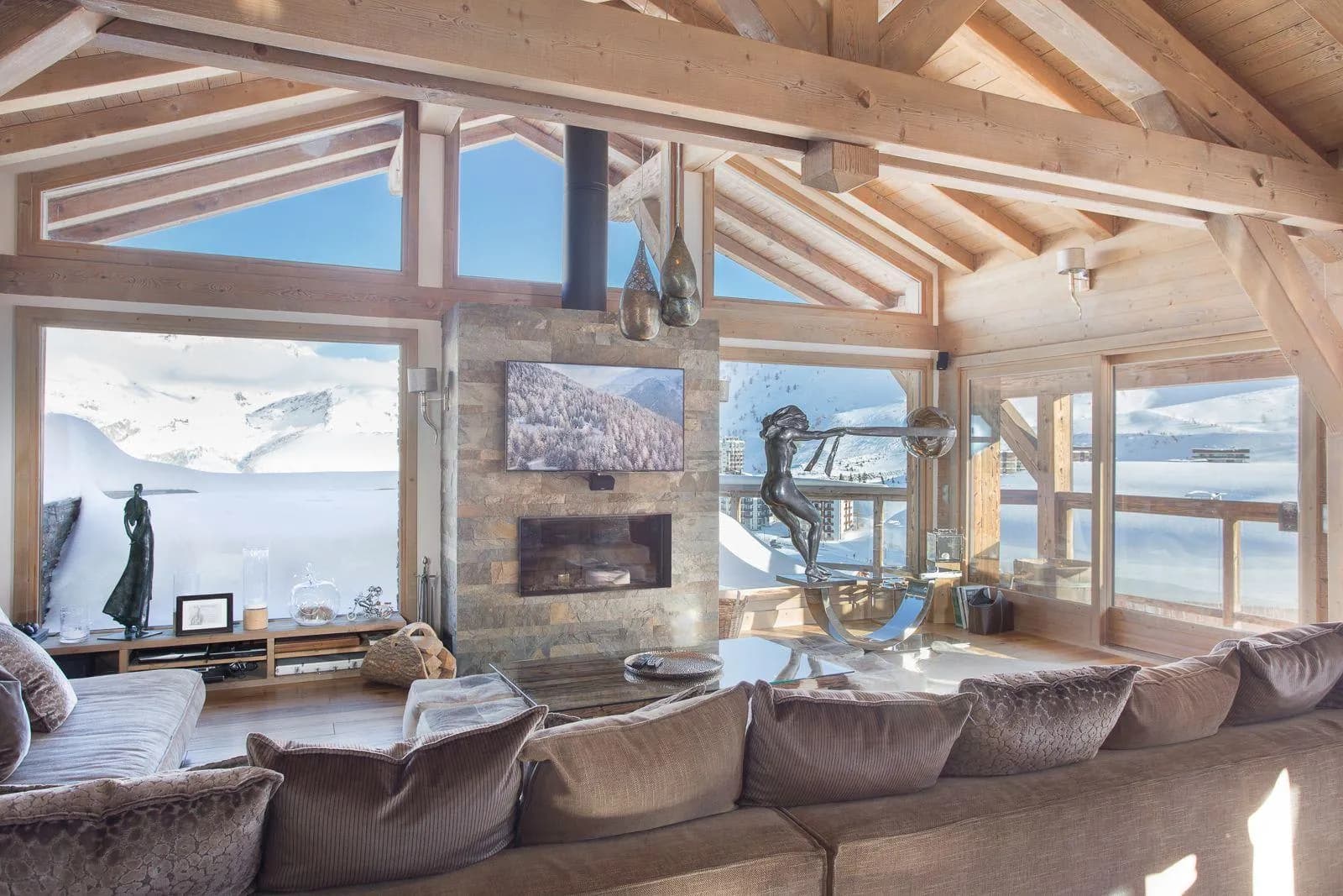 Living area with stone fireplace and floor-to-ceiling mountain views