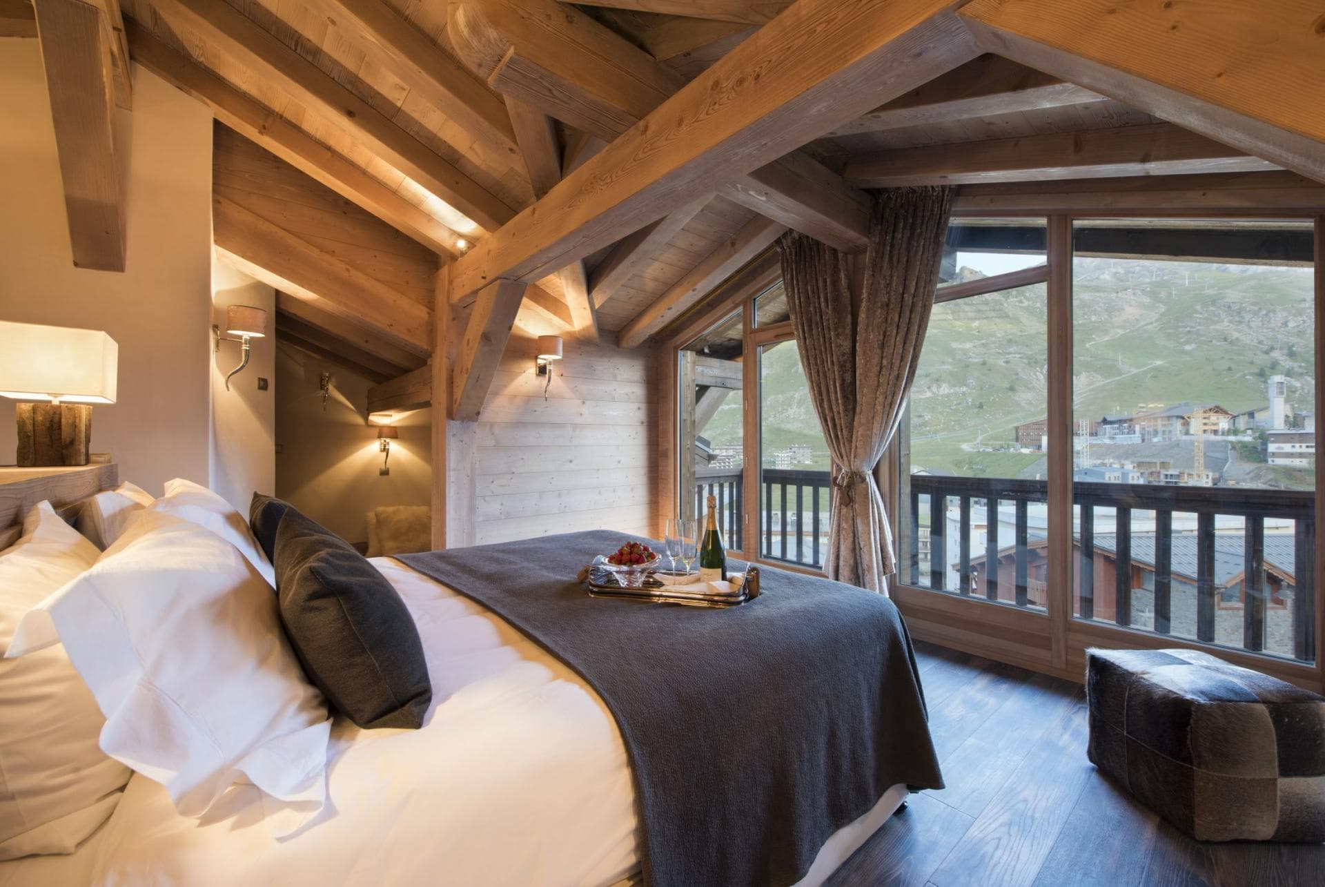 Loft bedroom with exposed timber beams and mountain village views