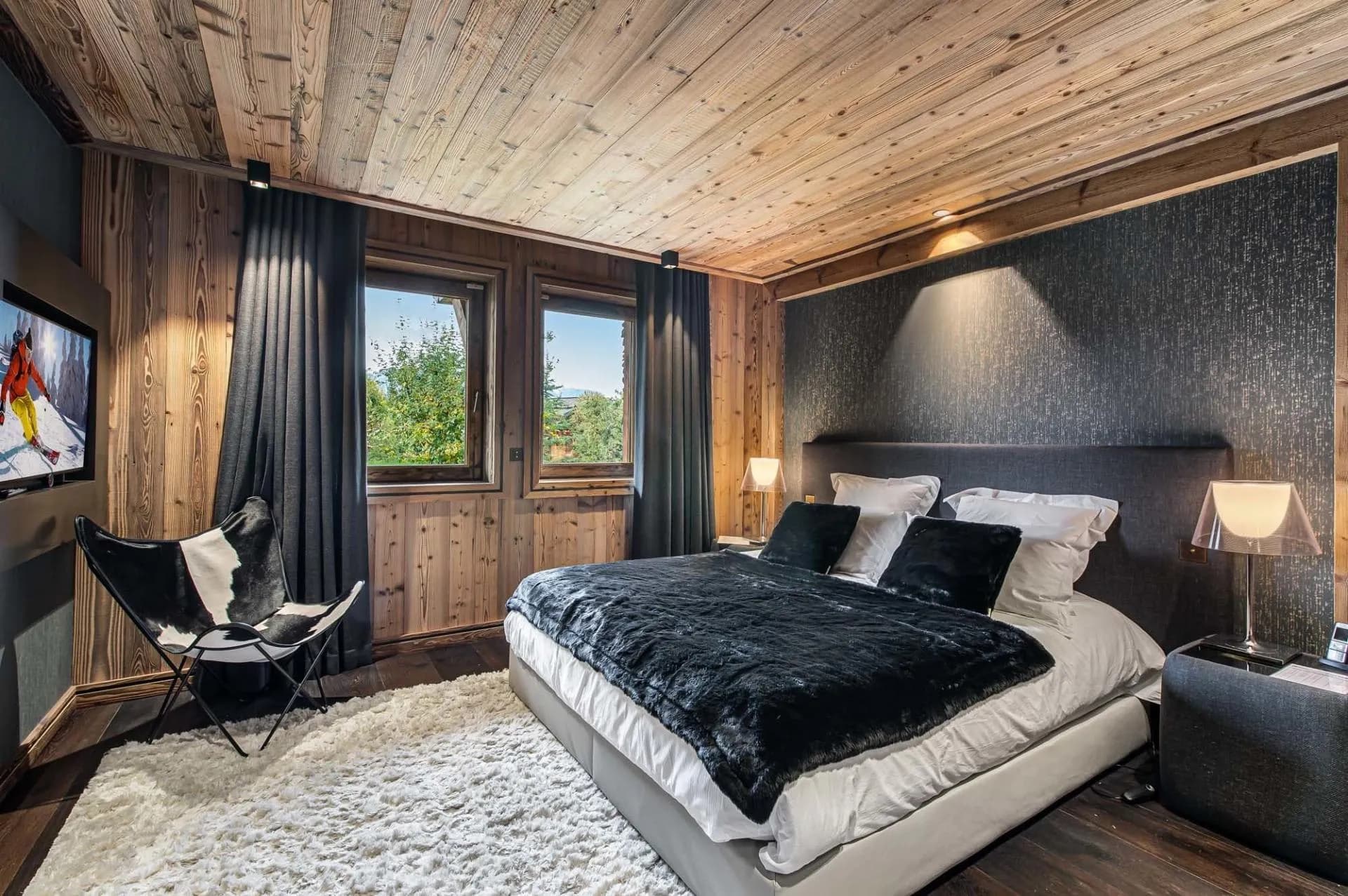 Double bedroom with dark bed linen and timber walls