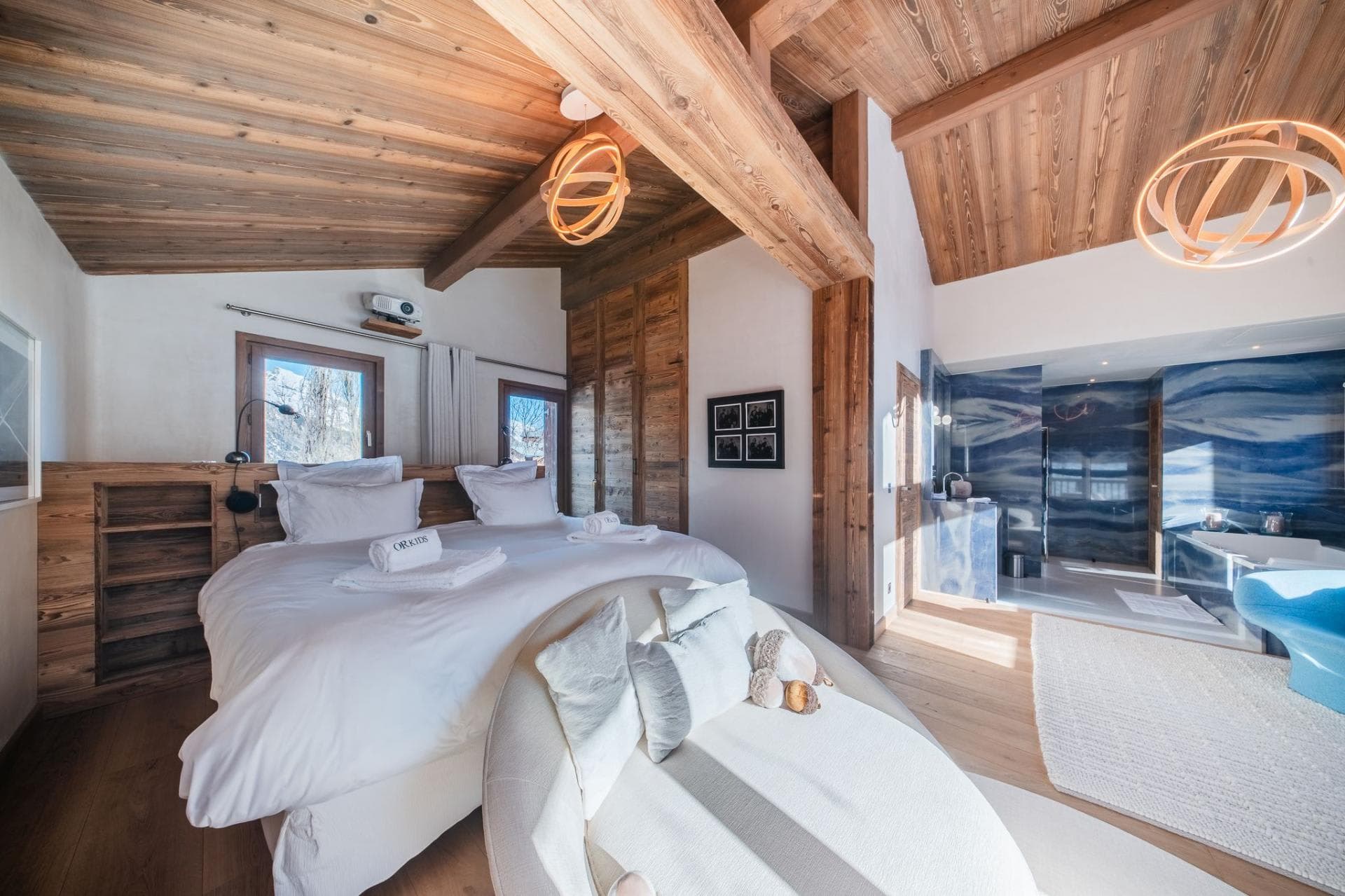 Primary suite with king bed, wall projector, and open ensuite bathroom