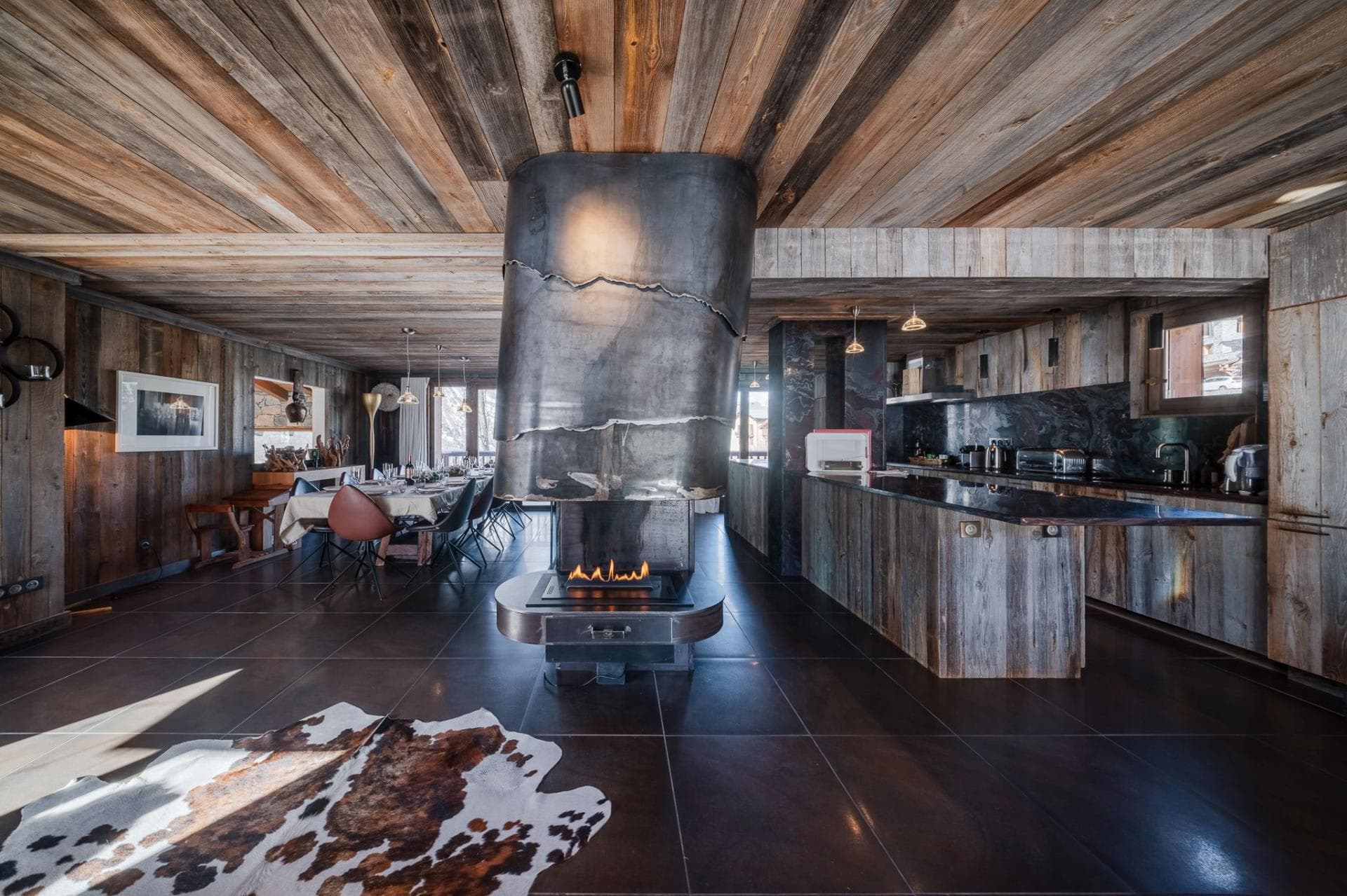 Open-plan living area with sculptural central fireplace and reclaimed wood finishes