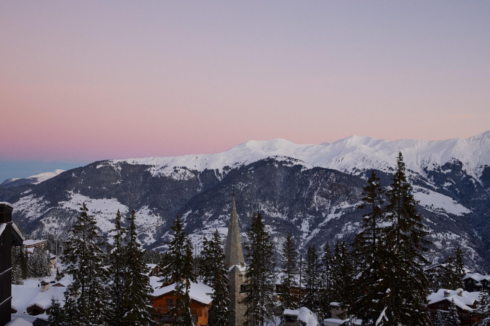 Village and mountain views with pink sunset over snow-capped peaks