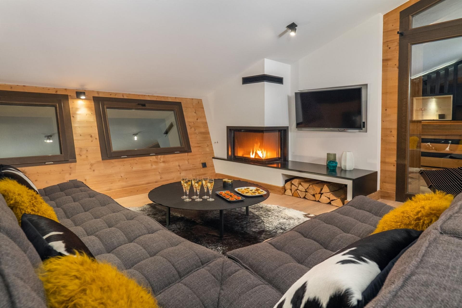 Living area with wood-burning fireplace, wall-mounted TV, and low-profile sectional seating