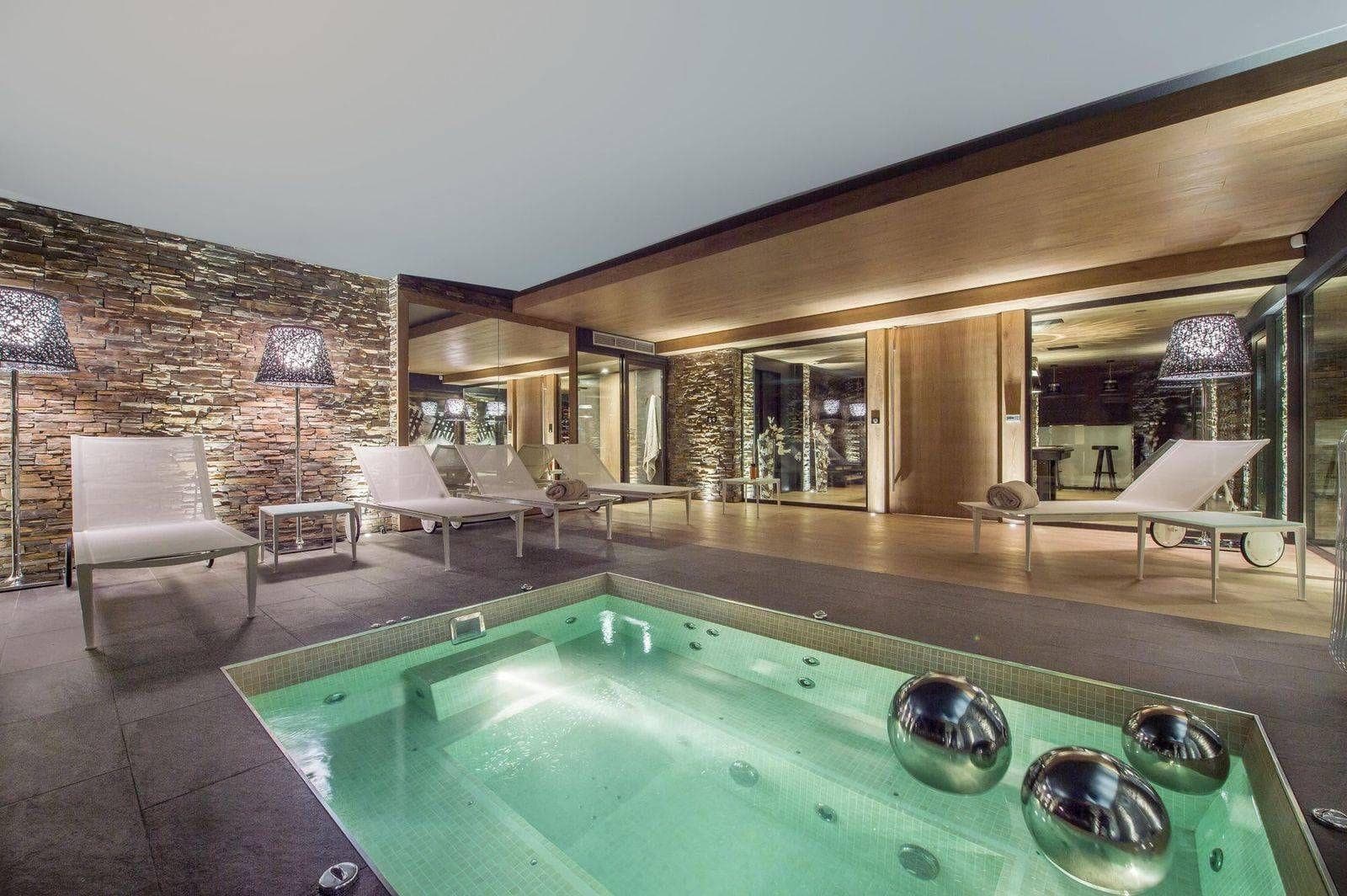 Indoor spa area with heated plunge pool and poolside lounge chairs