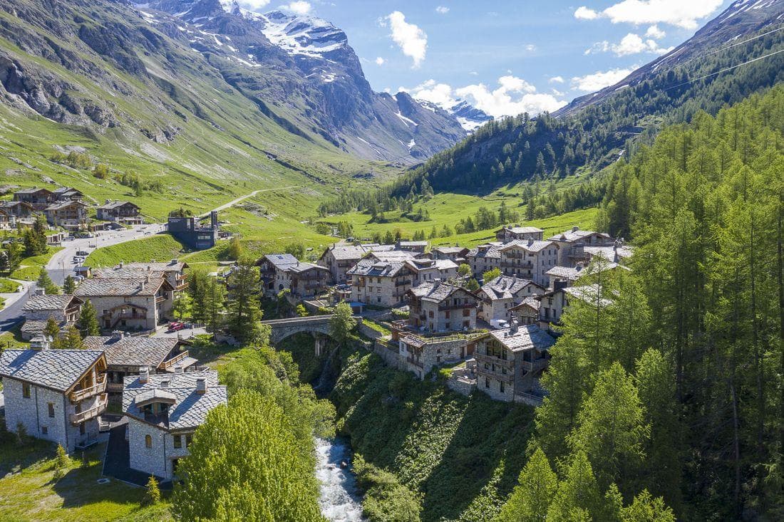 Aerial view of alpine village with stone chalets and river access