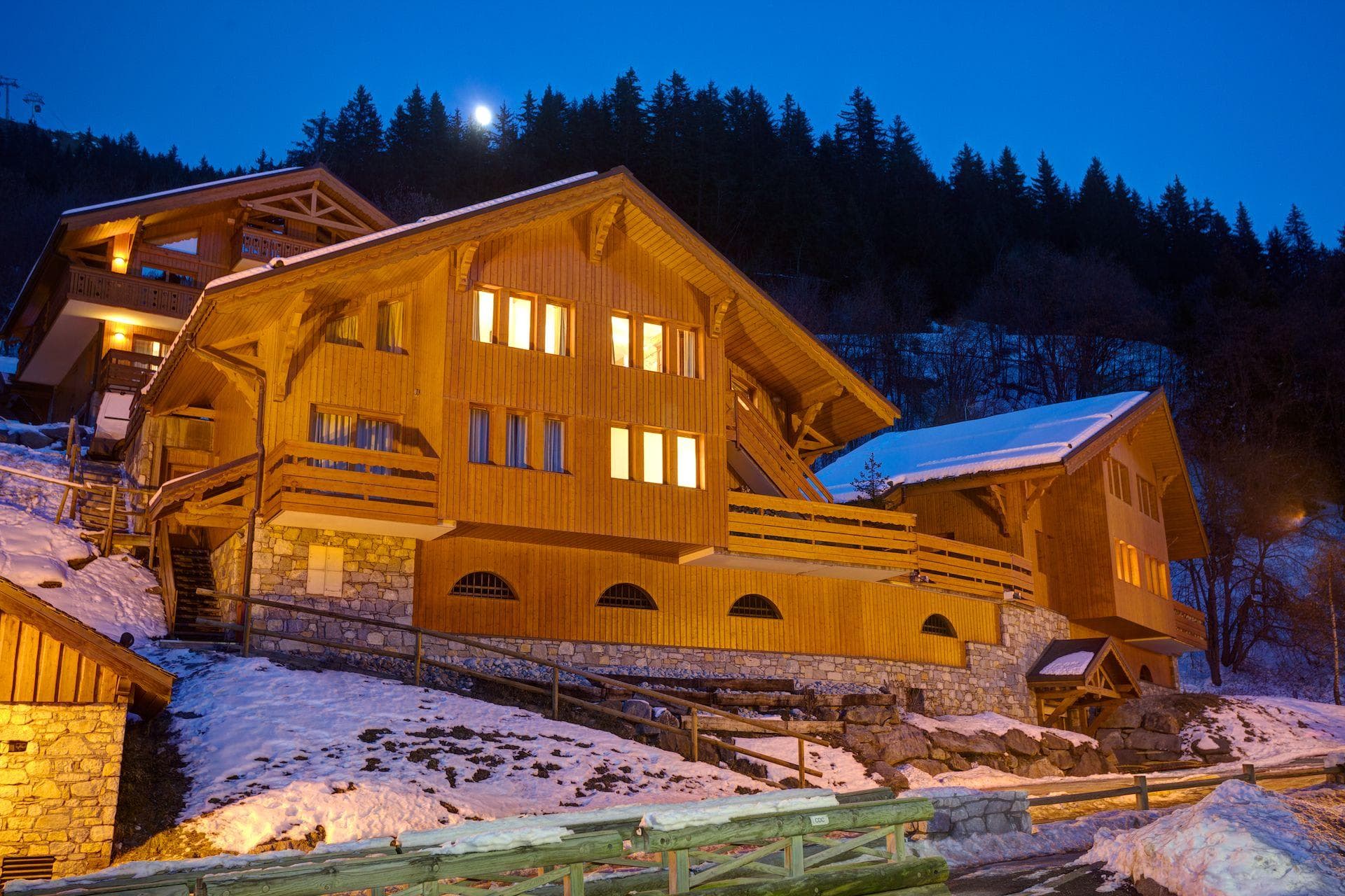 Ski-in/ski-out chalet with timber exterior and illuminated balconies at dusk