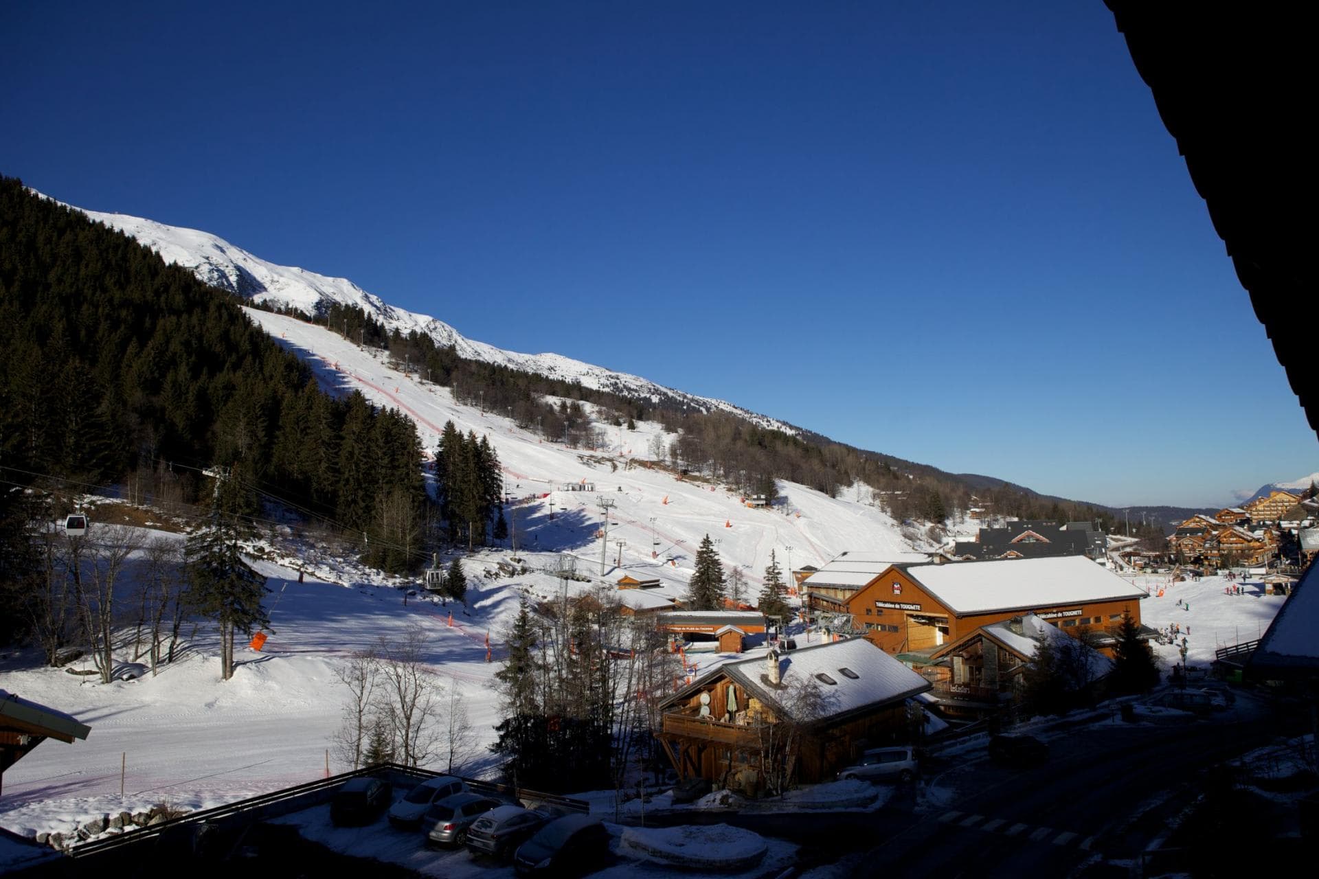 Balcony view of ski slopes and lift base with mountain backdrop