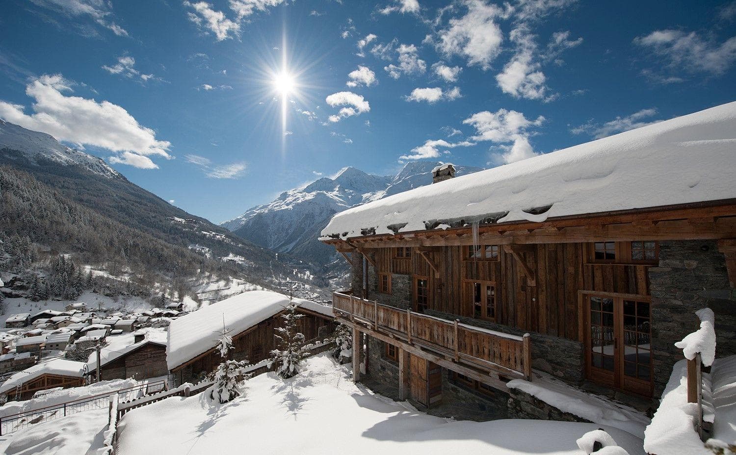 Ski-in chalet exterior with wrap-around balcony and alpine valley views