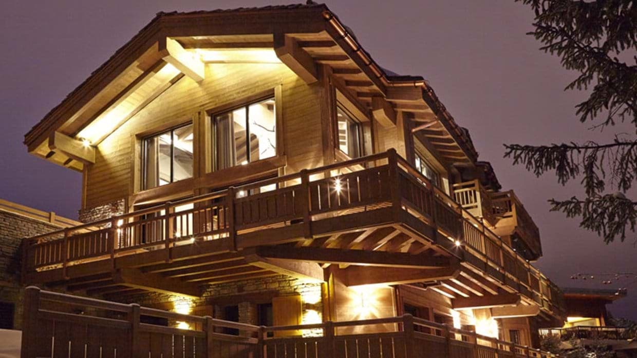 Chalet exterior at dusk with integrated lighting and wraparound timber balconies