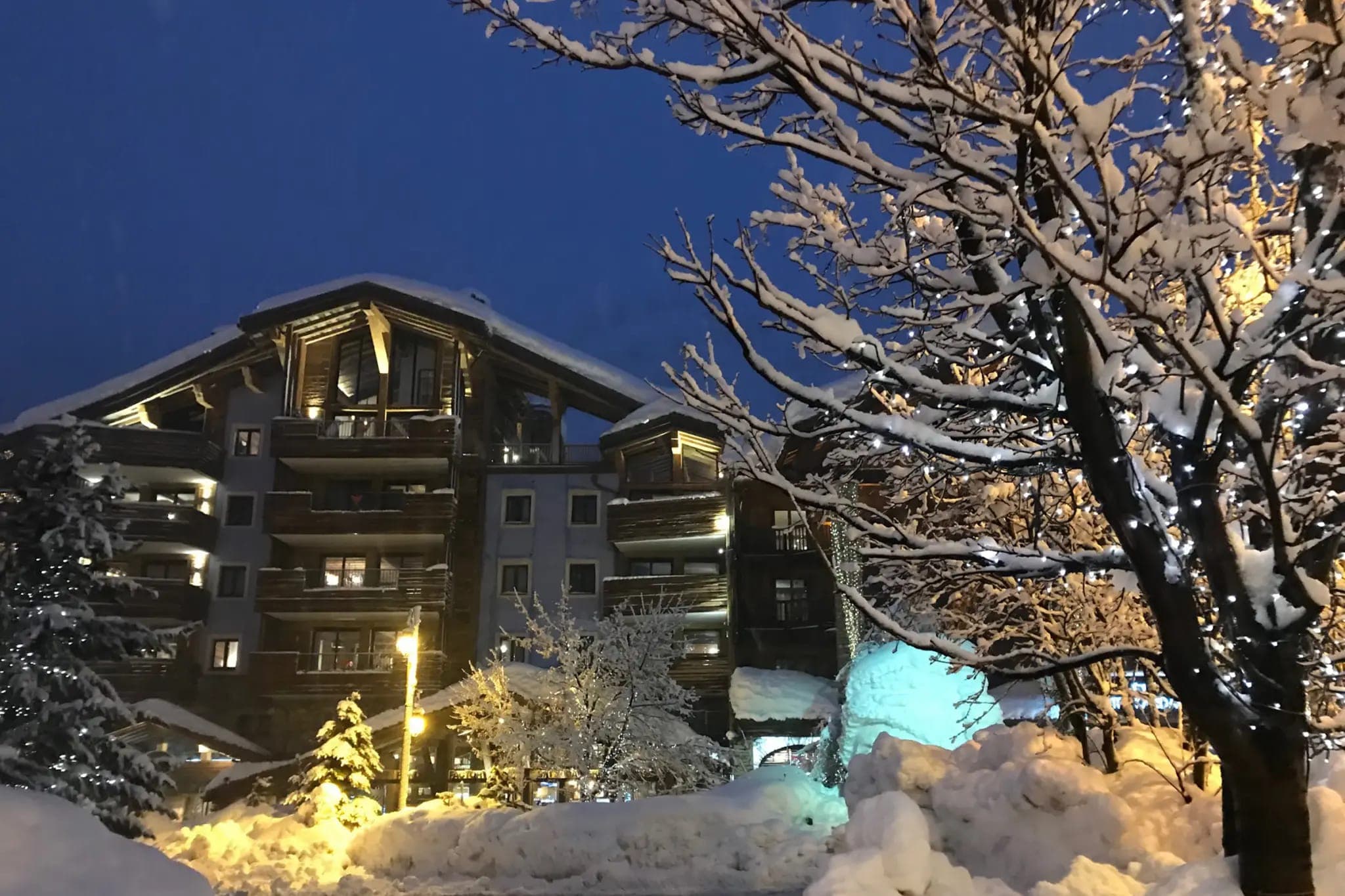Ski-in, ski-out timber chalet building with private balconies and exterior lighting