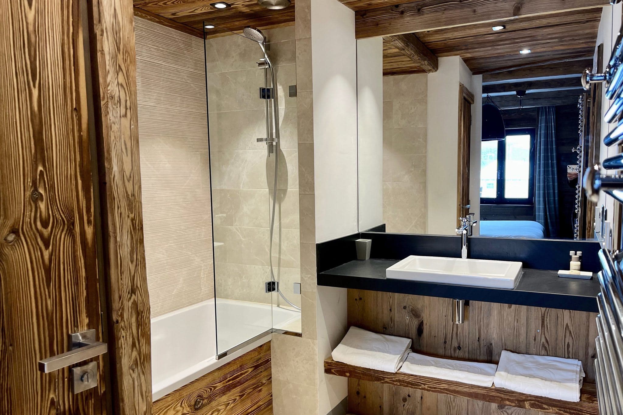 Bathroom with glass-screened soaking tub and heated towel rack
