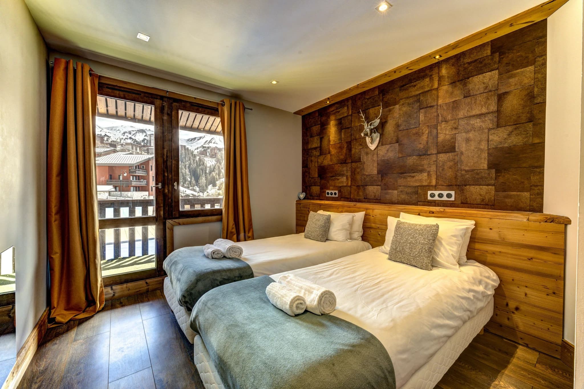 Guest bedroom with two twin beds and balcony mountain views