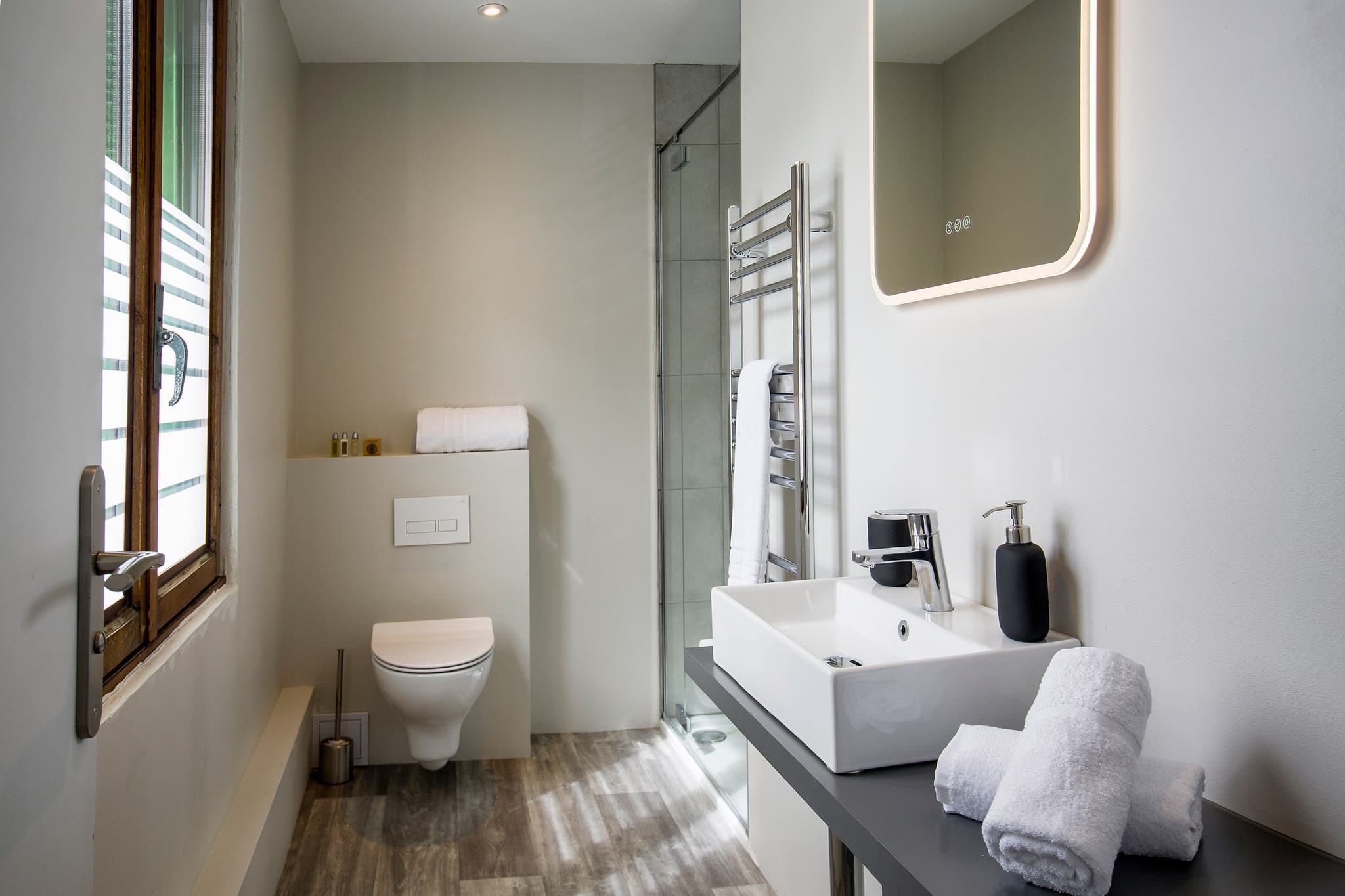 Bathroom with walk-in shower, heated towel rail, and backlit mirror