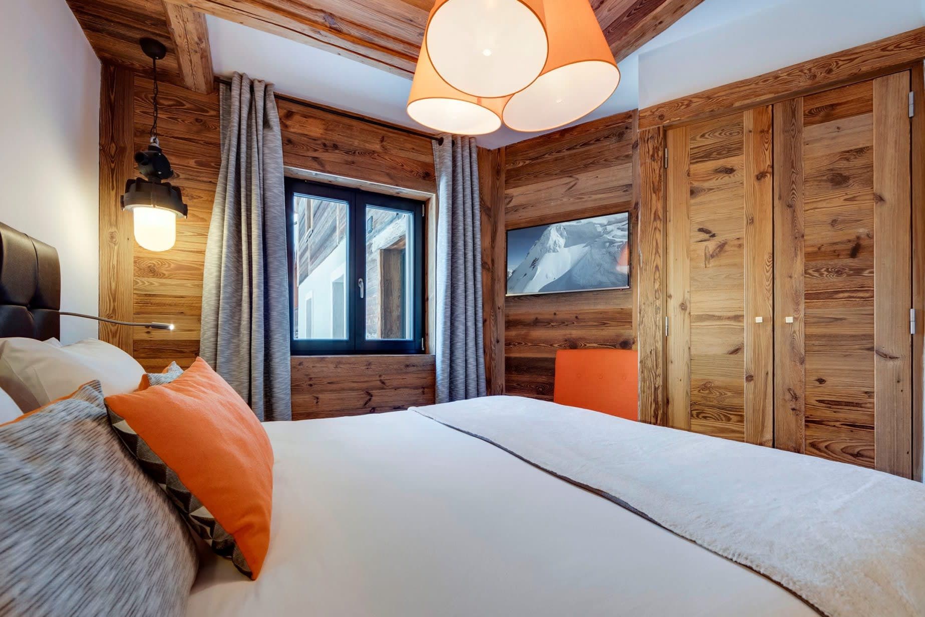 Bedroom with wood-paneled walls, wall-mounted TV, and integrated storage closets