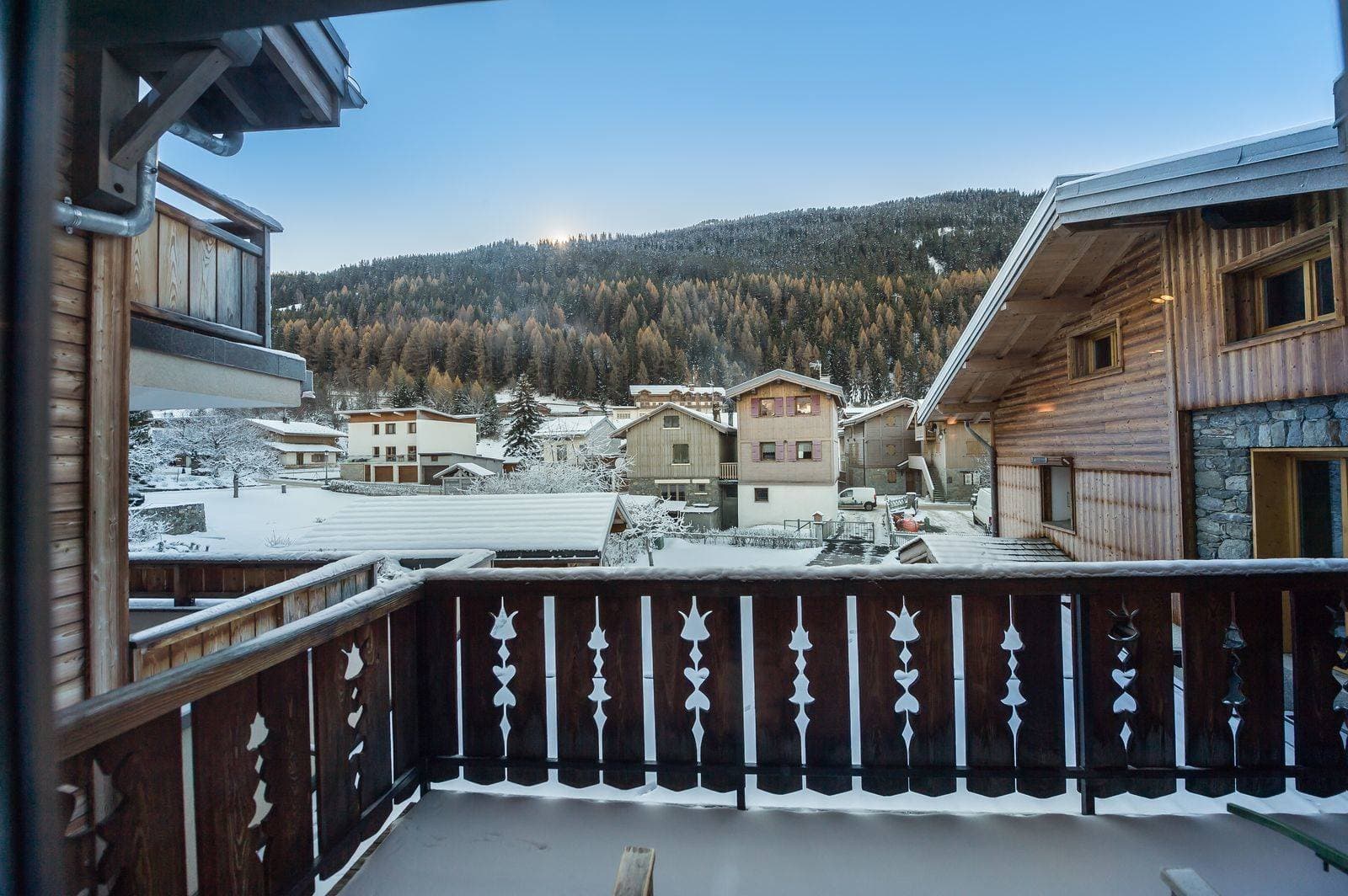Private balcony with village views and alpine forest backdrop