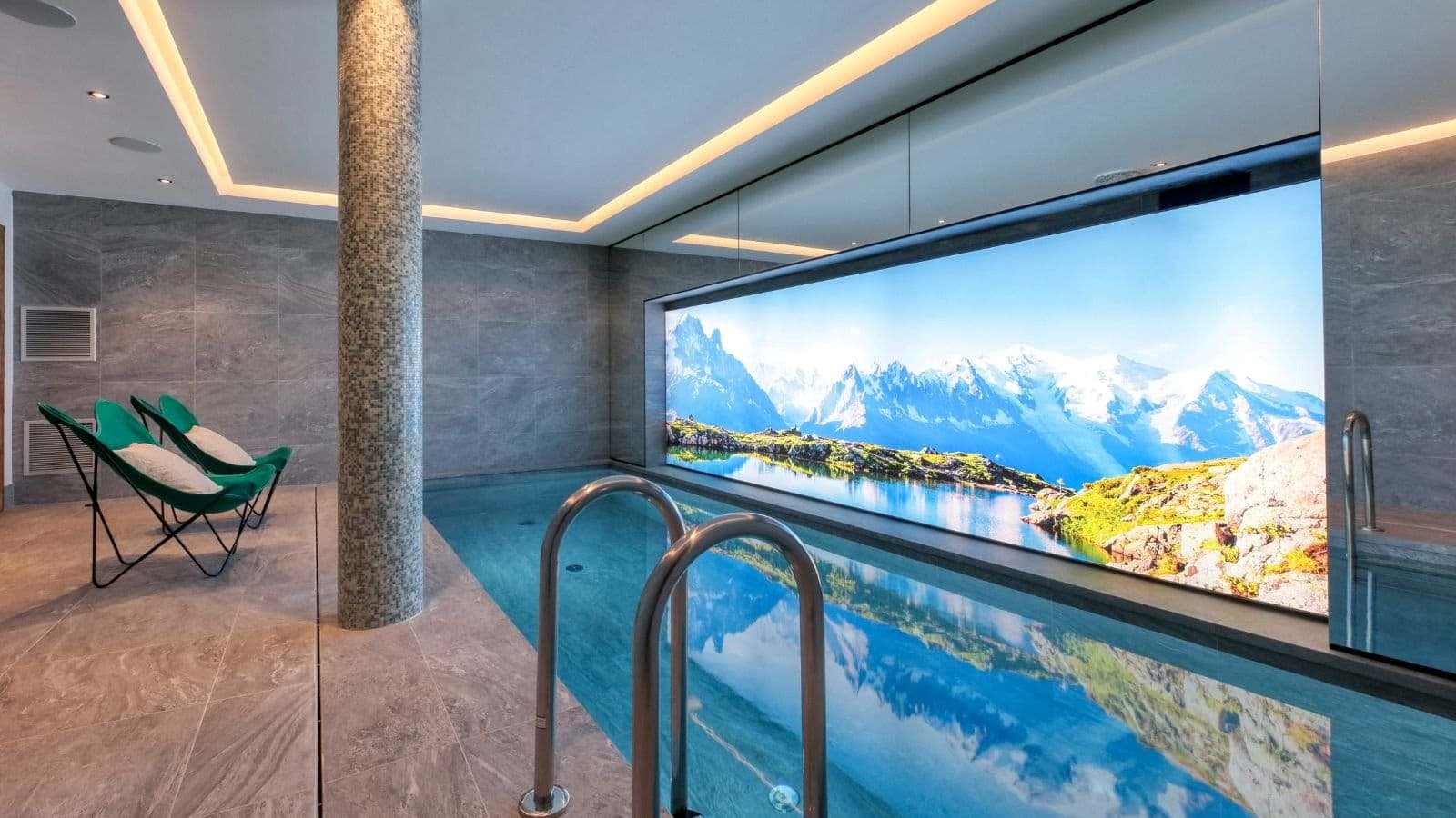 Indoor pool with large mountain mural and poolside butterfly chairs