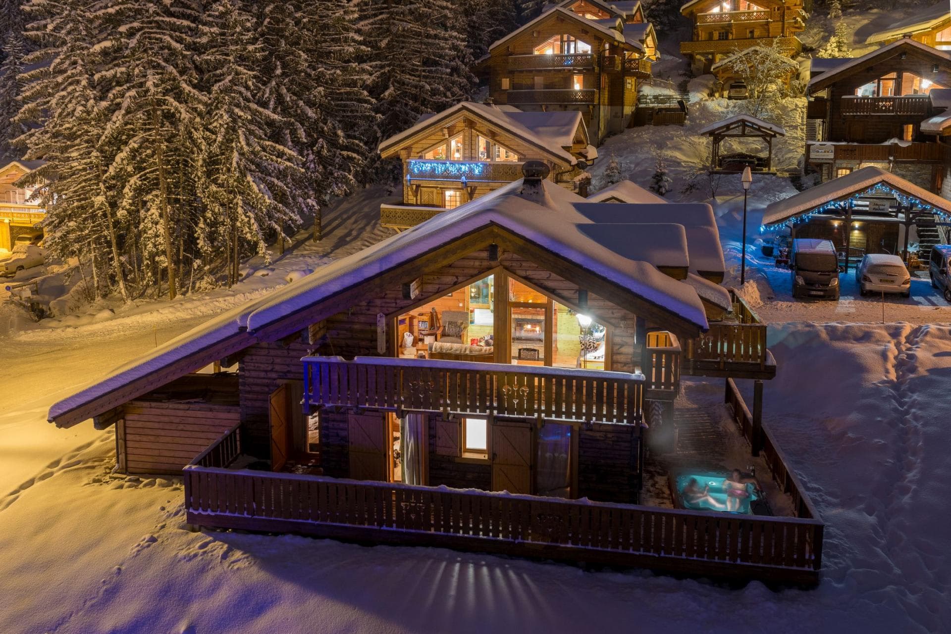 Ski-in chalet exterior with private balcony and lit outdoor hot tub