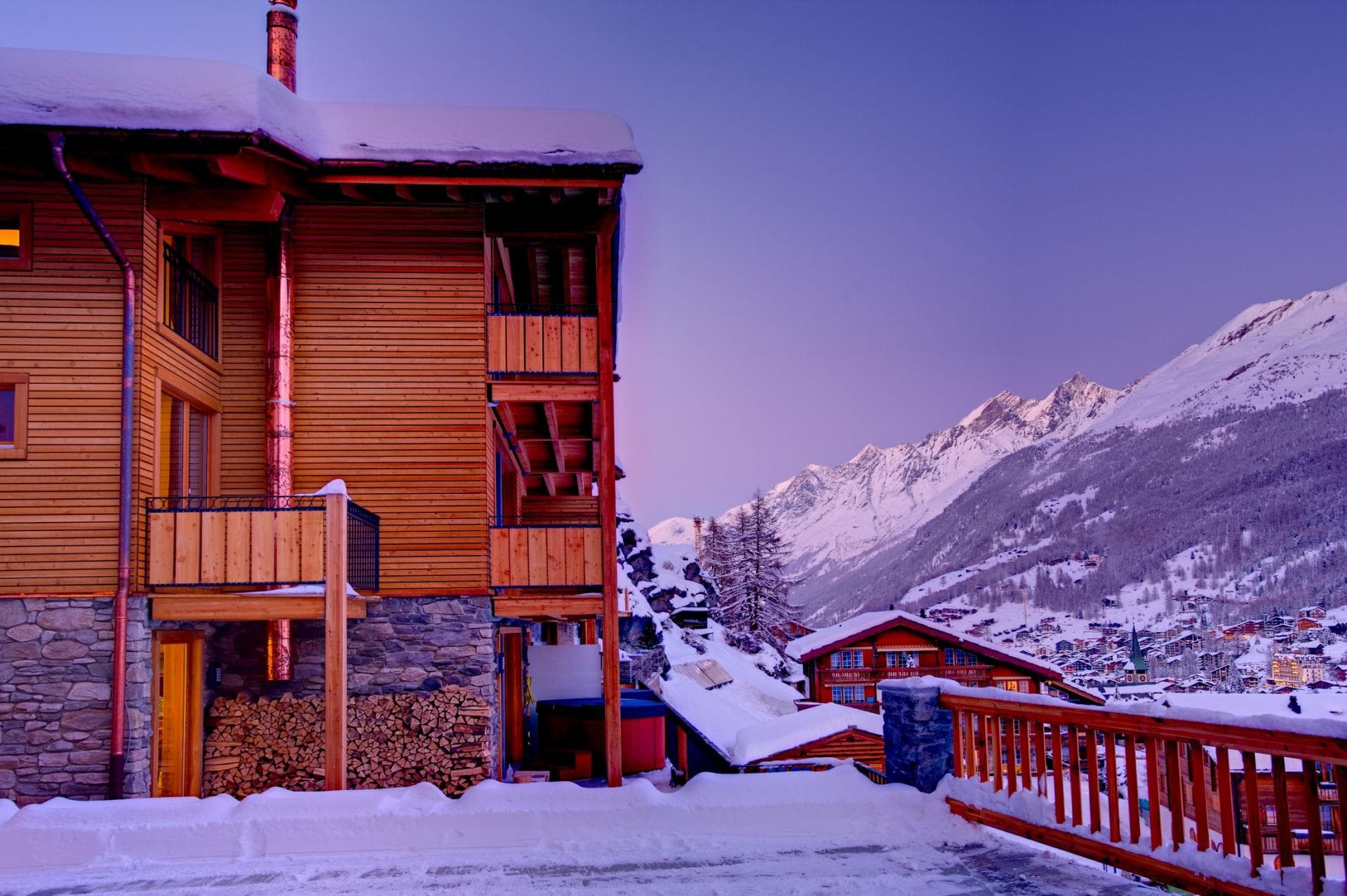 Chalet exterior with private balconies and mountain views; ground floor firewood storage