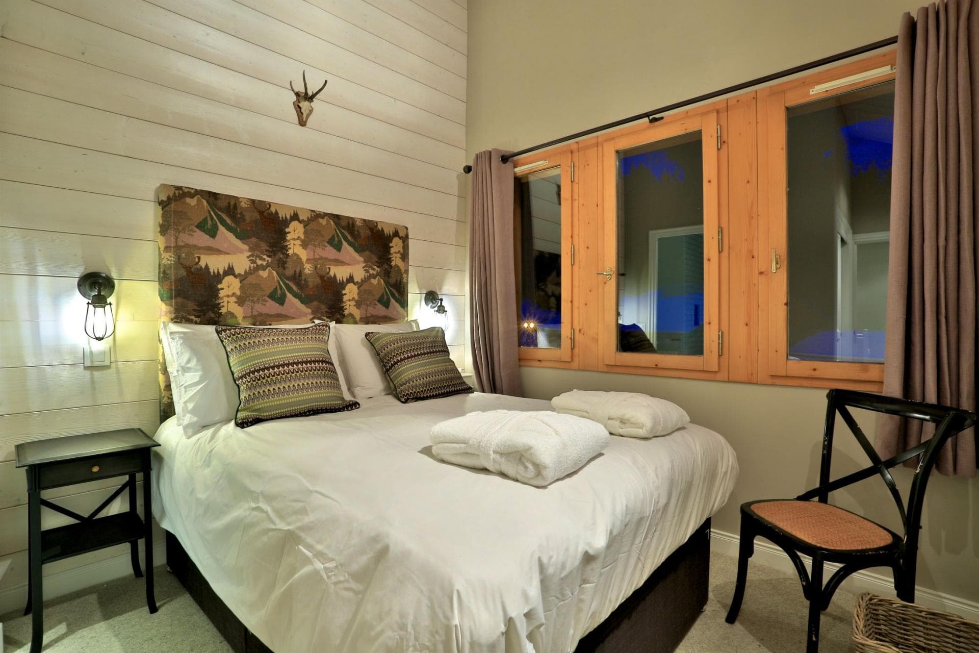 Guest bedroom with queen bed and wood-paneled feature wall