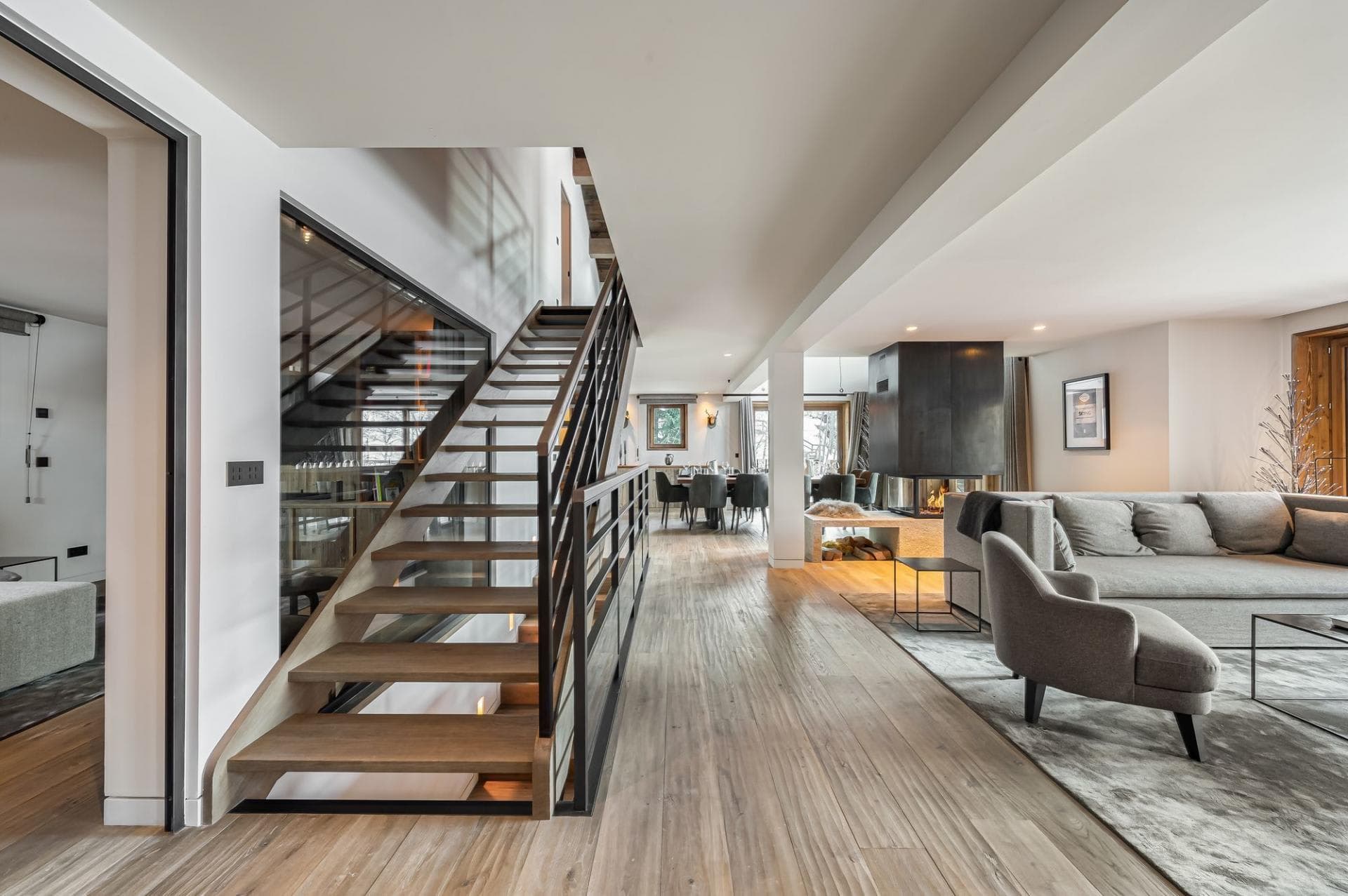 Open-plan living area with three-sided fireplace and floating timber staircase