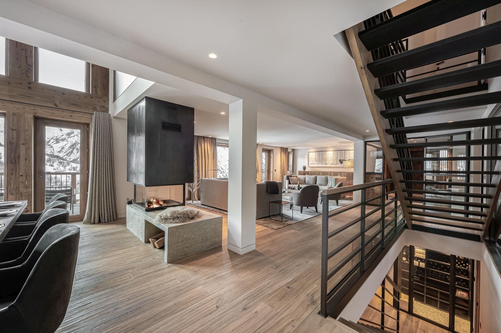 Open-plan living area with three-sided fireplace and glass-walled wine cellar