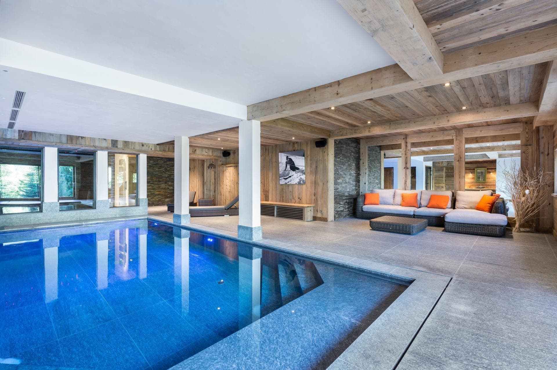 Indoor pool with sectional lounge seating and wood-beamed ceiling