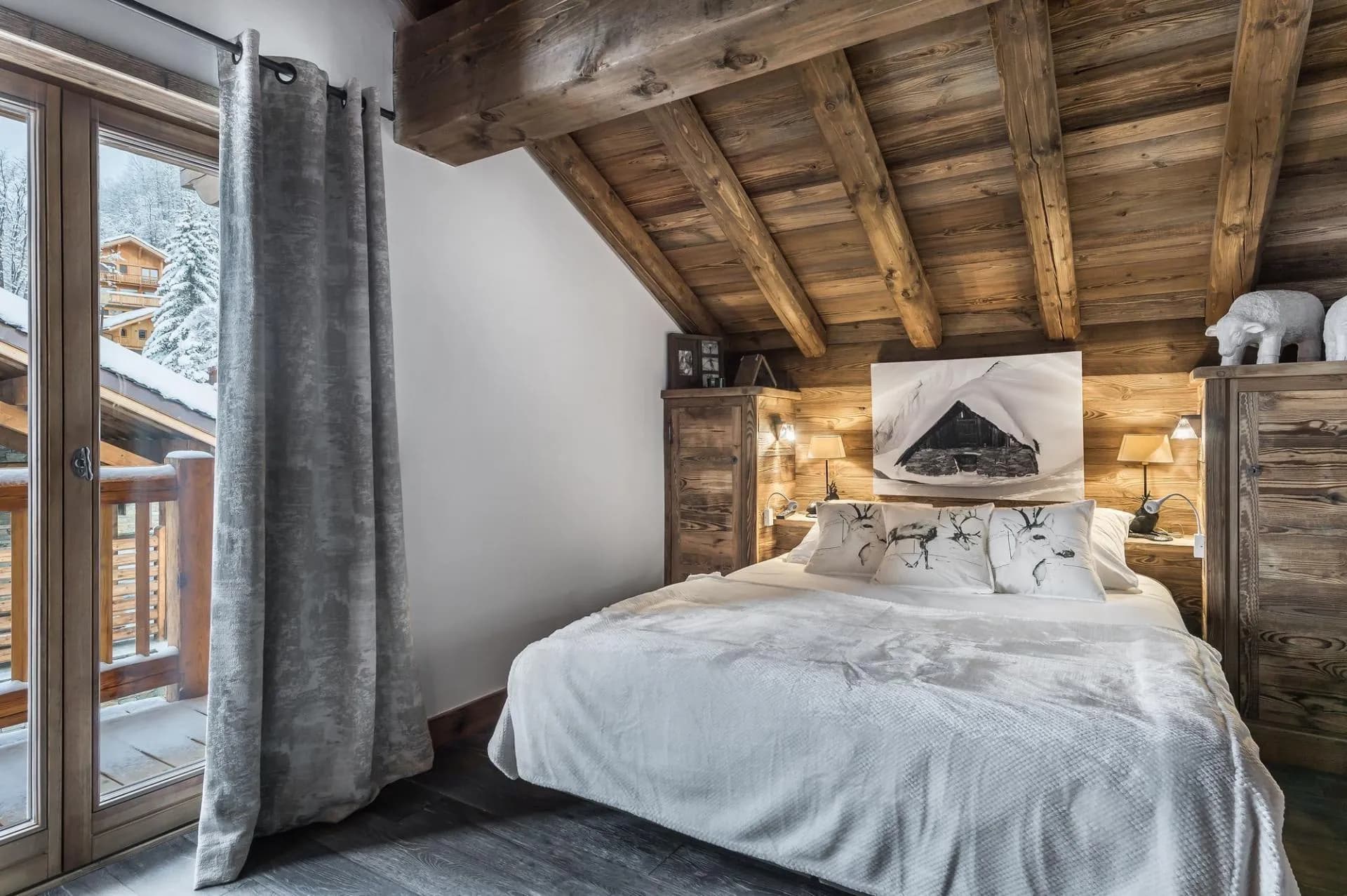 Double bedroom beneath a vaulted timber ceiling with a private balcony