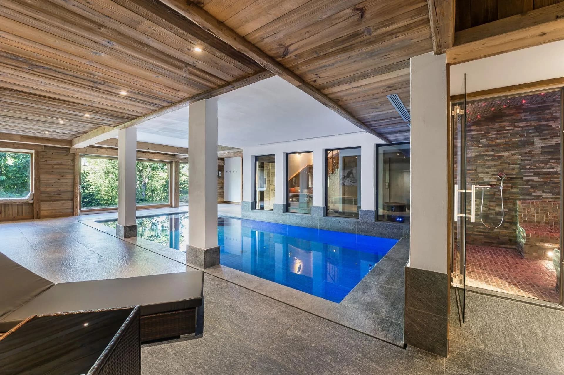 Indoor swimming pool with a glass-fronted hammam and forest views