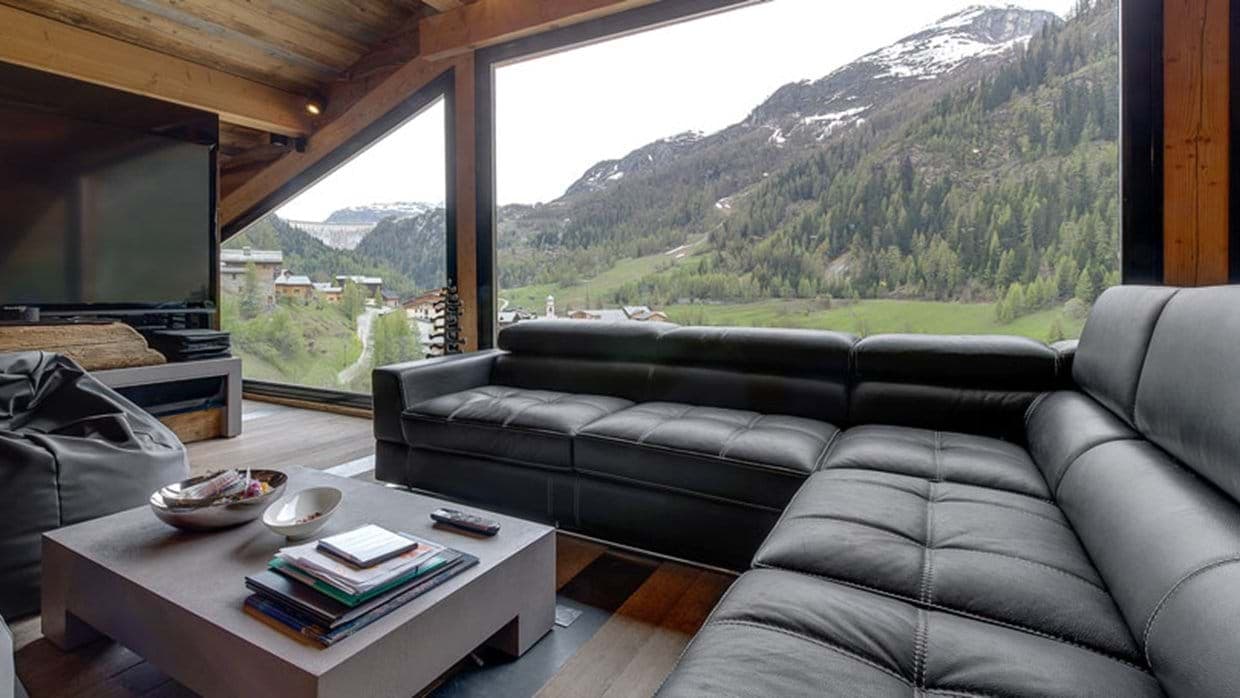 Living area with leather sectional and floor-to-ceiling mountain views