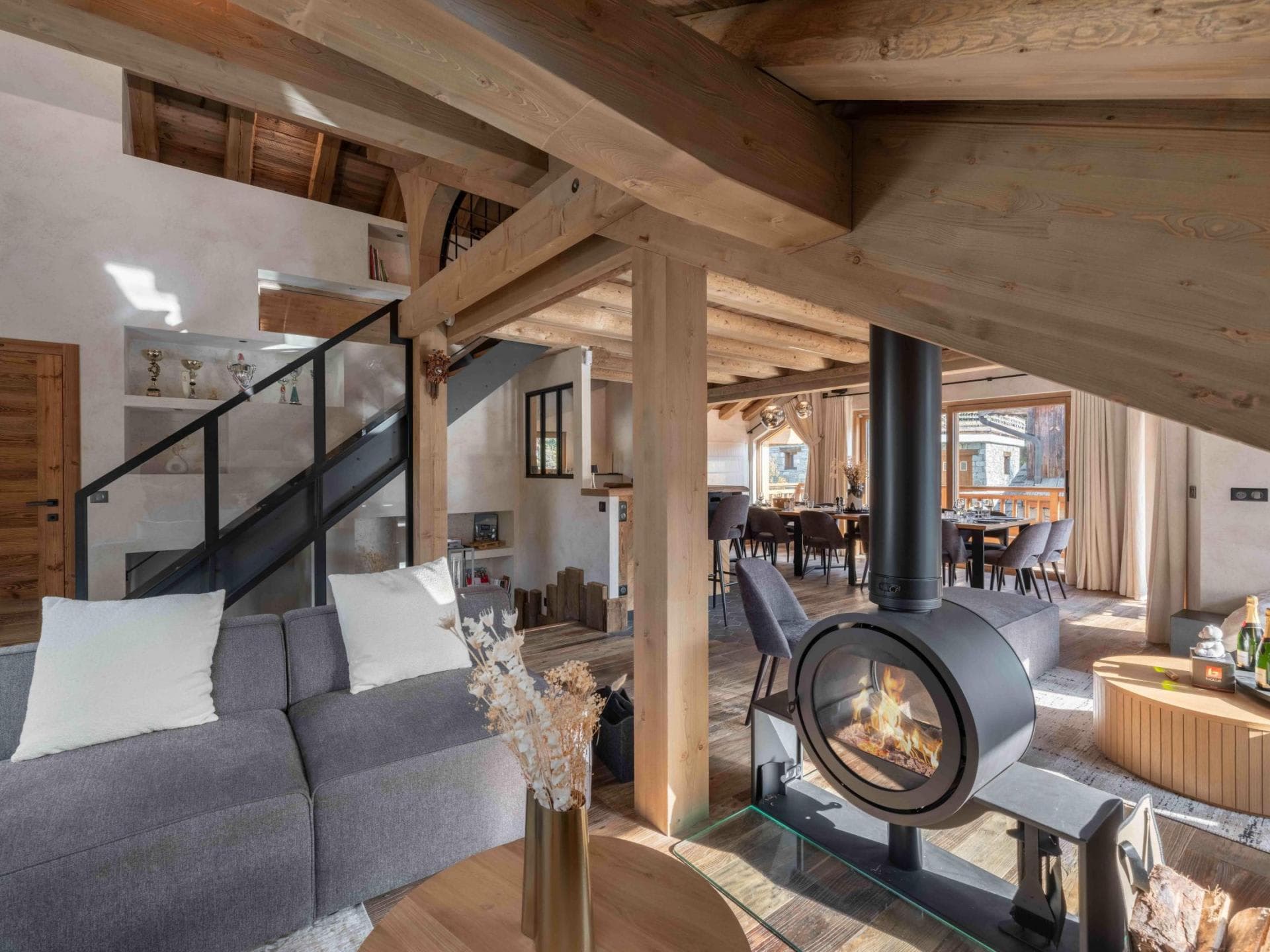 Open-plan living area with circular wood-burning stove and timber beams