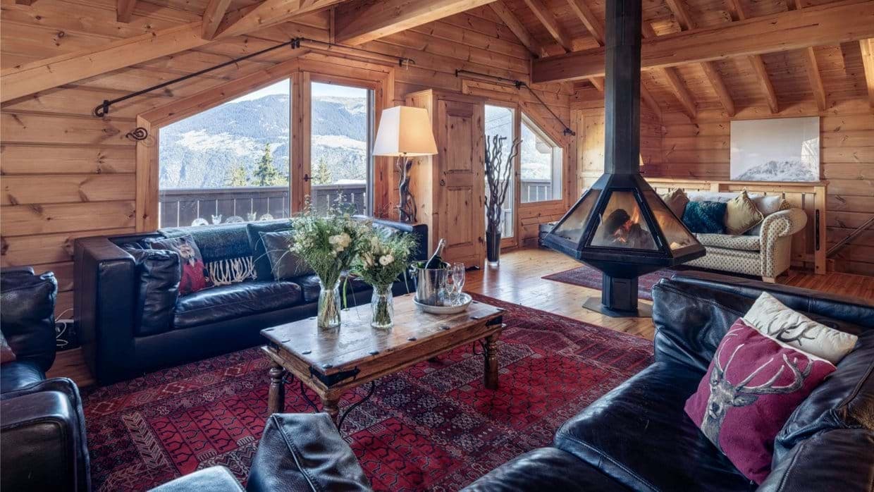 Living area with central wood-burning fireplace and mountain views
