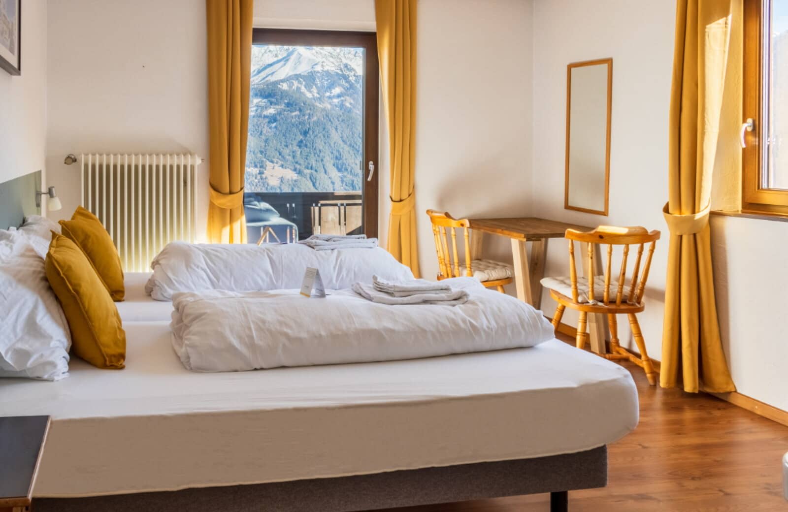 Twin bedroom with workspace and balcony access overlooking the mountains