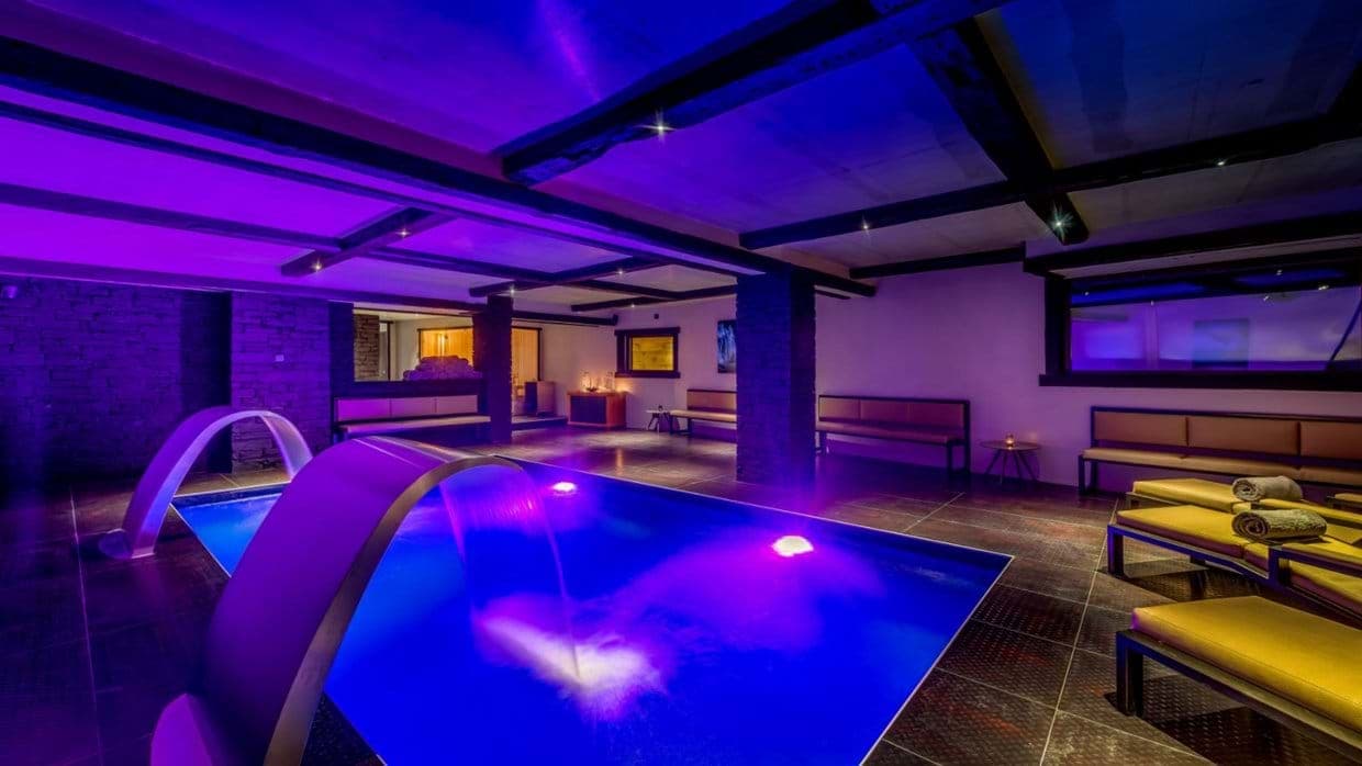 Indoor pool with swan neck water features and poolside loungers