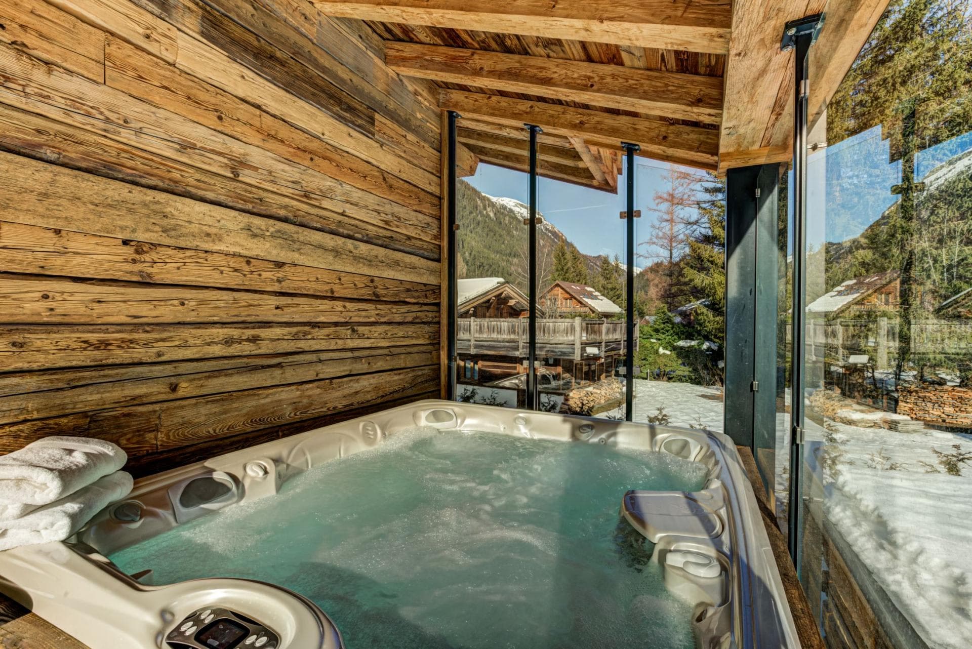 Covered outdoor hot tub with mountain views and glass windbreak