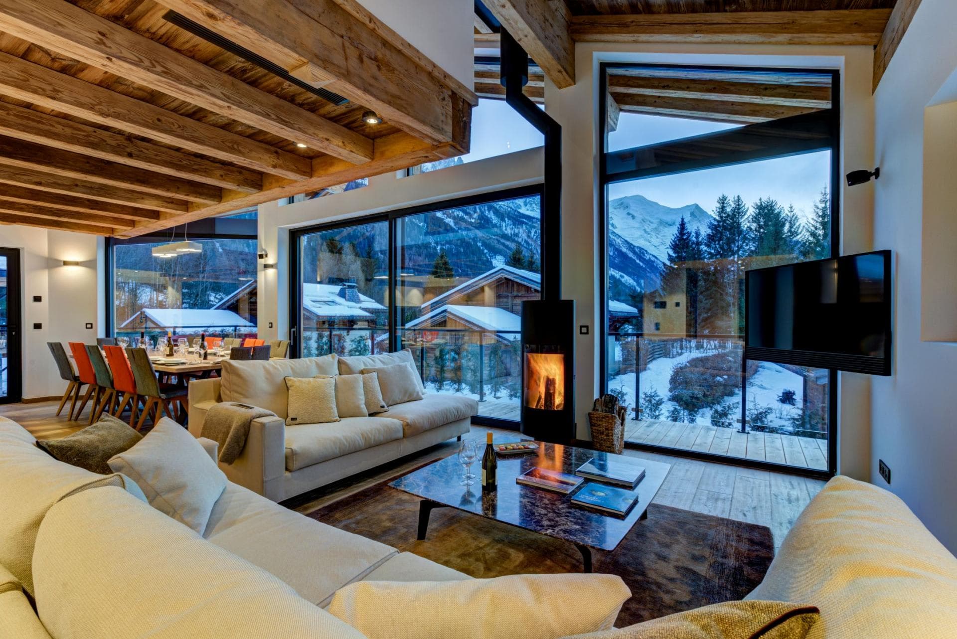 Open-plan living area with wood-burning stove and floor-to-ceiling mountain views