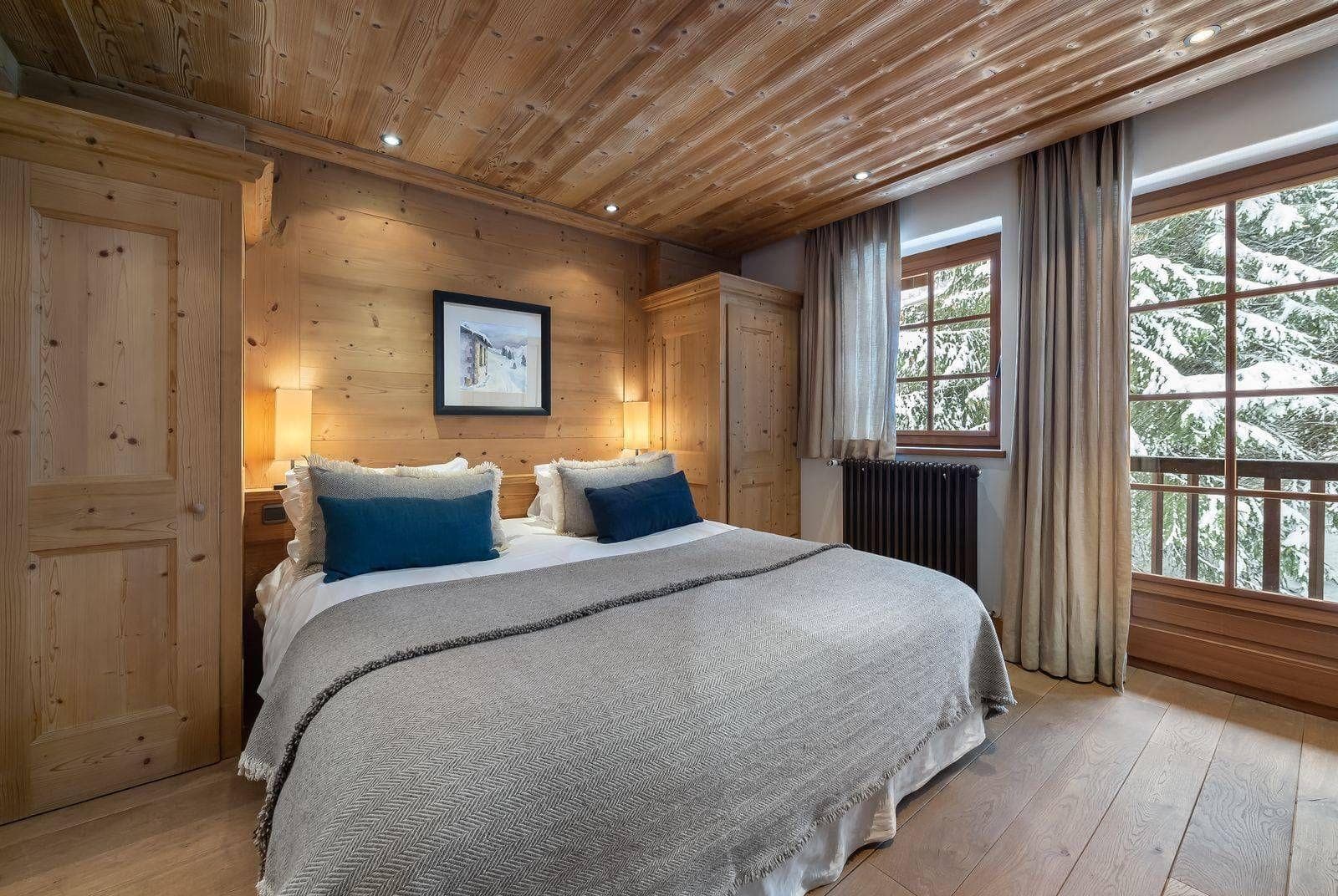 Wood-paneled bedroom with king bed and snow-covered forest views