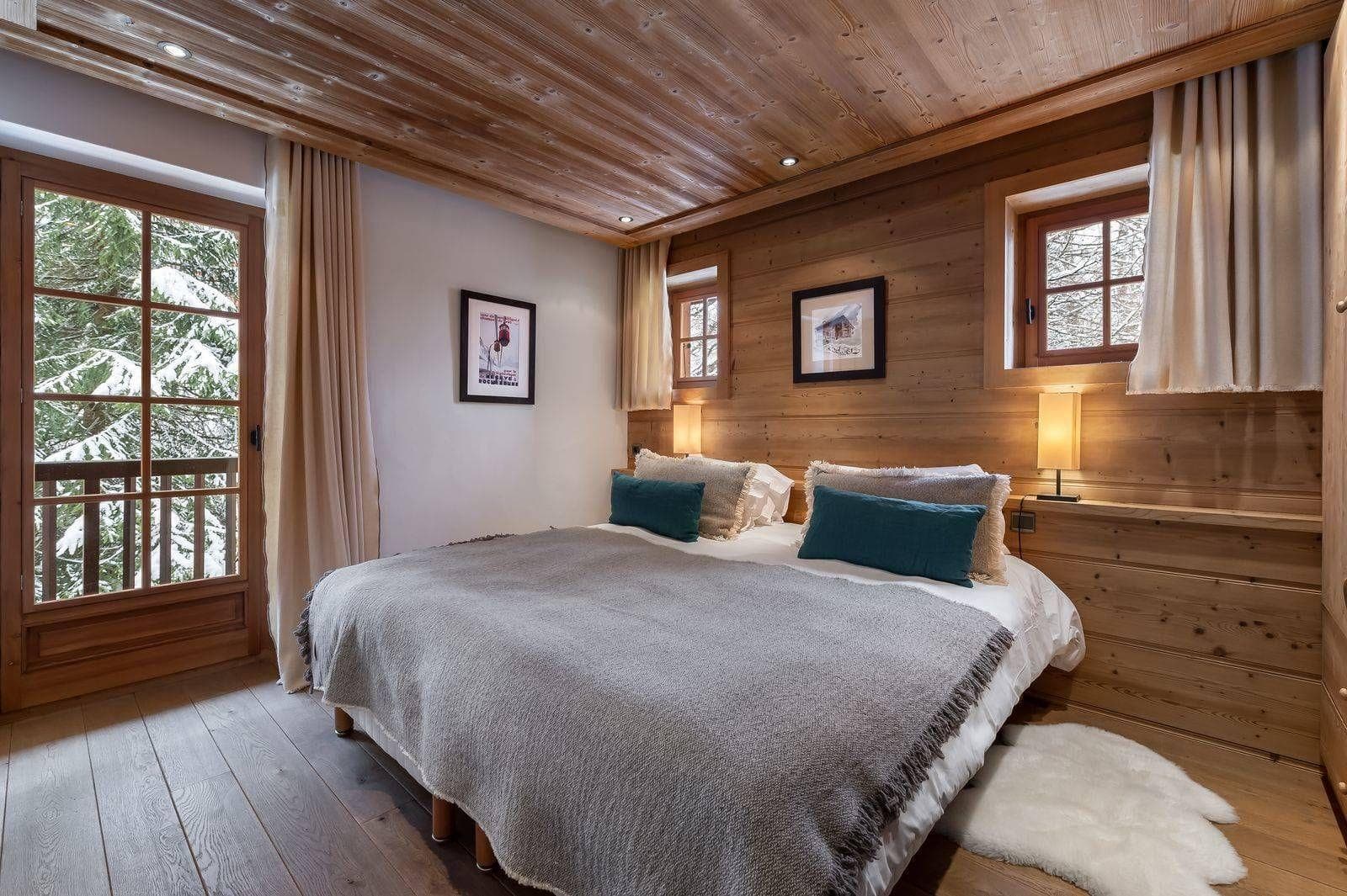 Double bedroom with timber walls and large windows