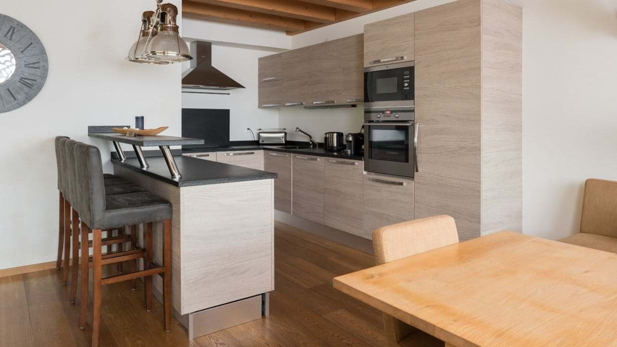 Kitchen with wall-mounted oven and breakfast bar seating for three