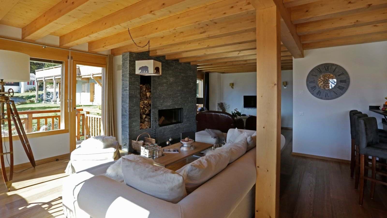 Living area with wood-burning fireplace, beam ceilings, and balcony access