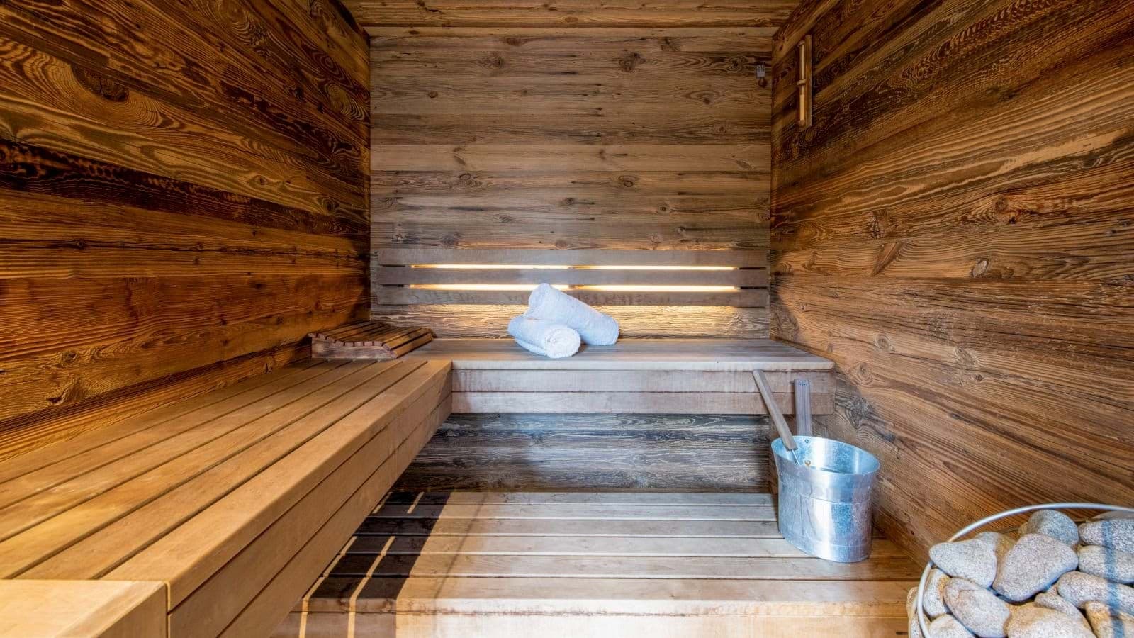 Private timber sauna with tiered bench seating and electric heater