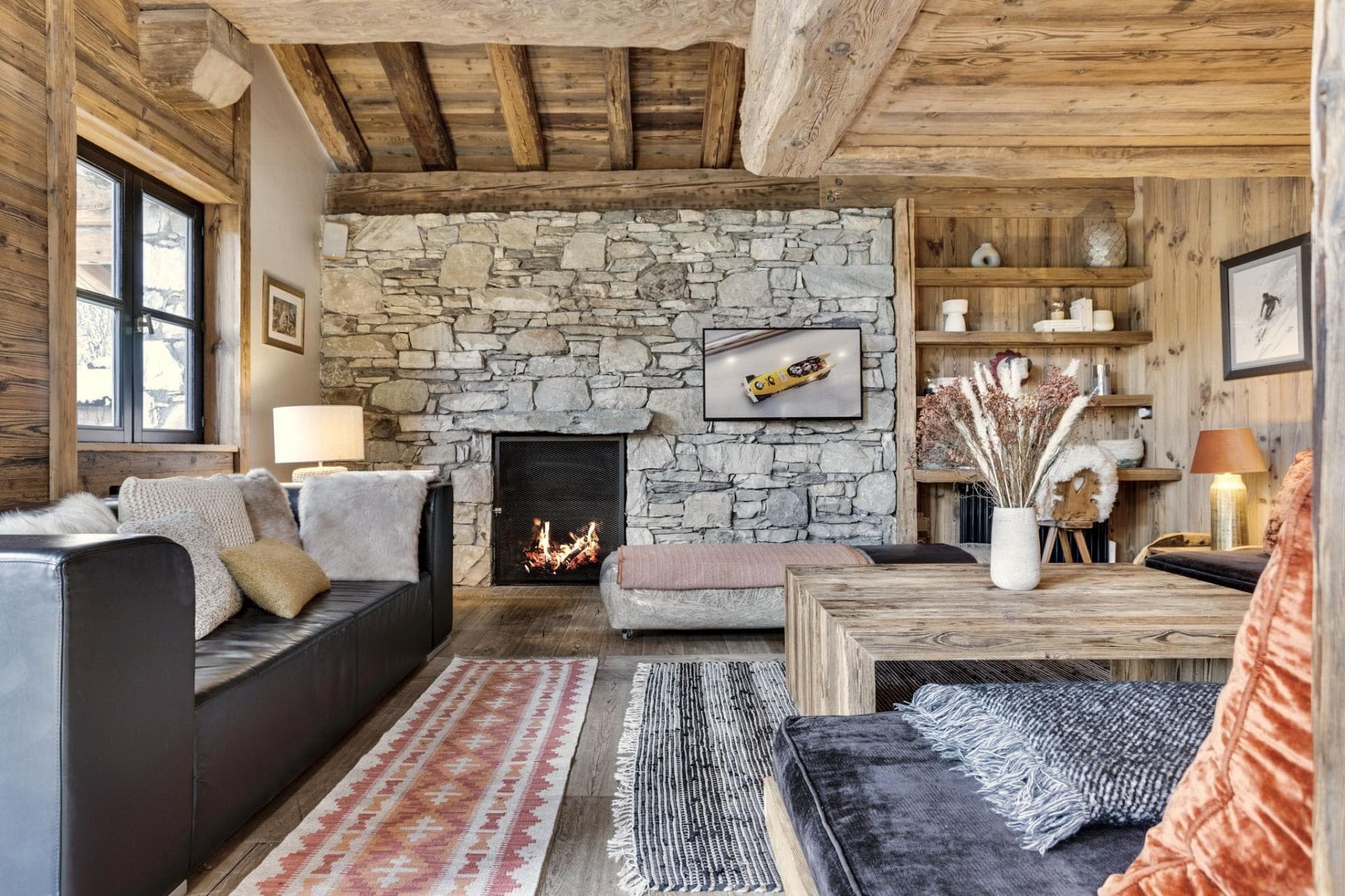 Living room with wood-burning fireplace and exposed stone wall