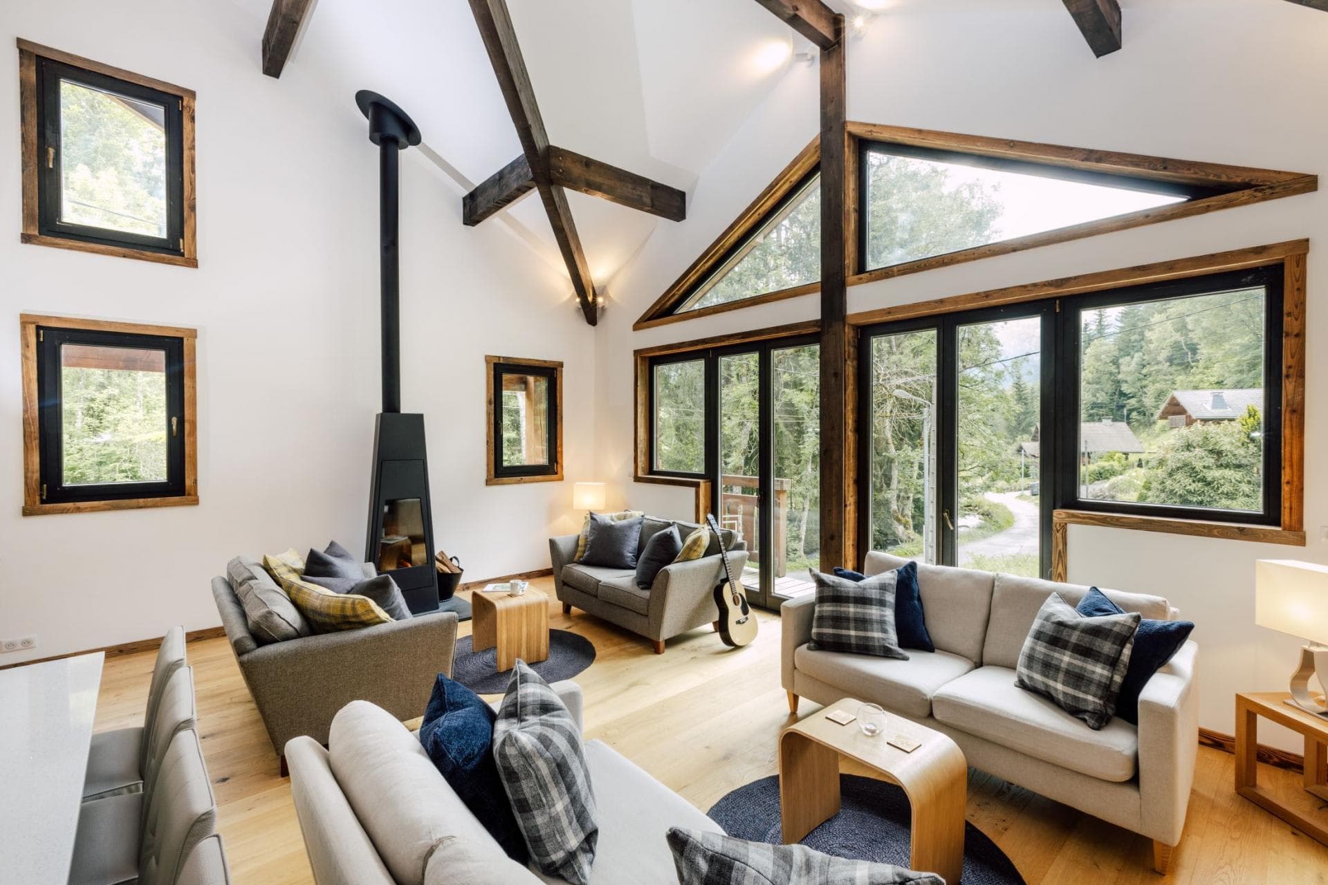 Living area with wood-burning stove, vaulted ceilings, and forest views