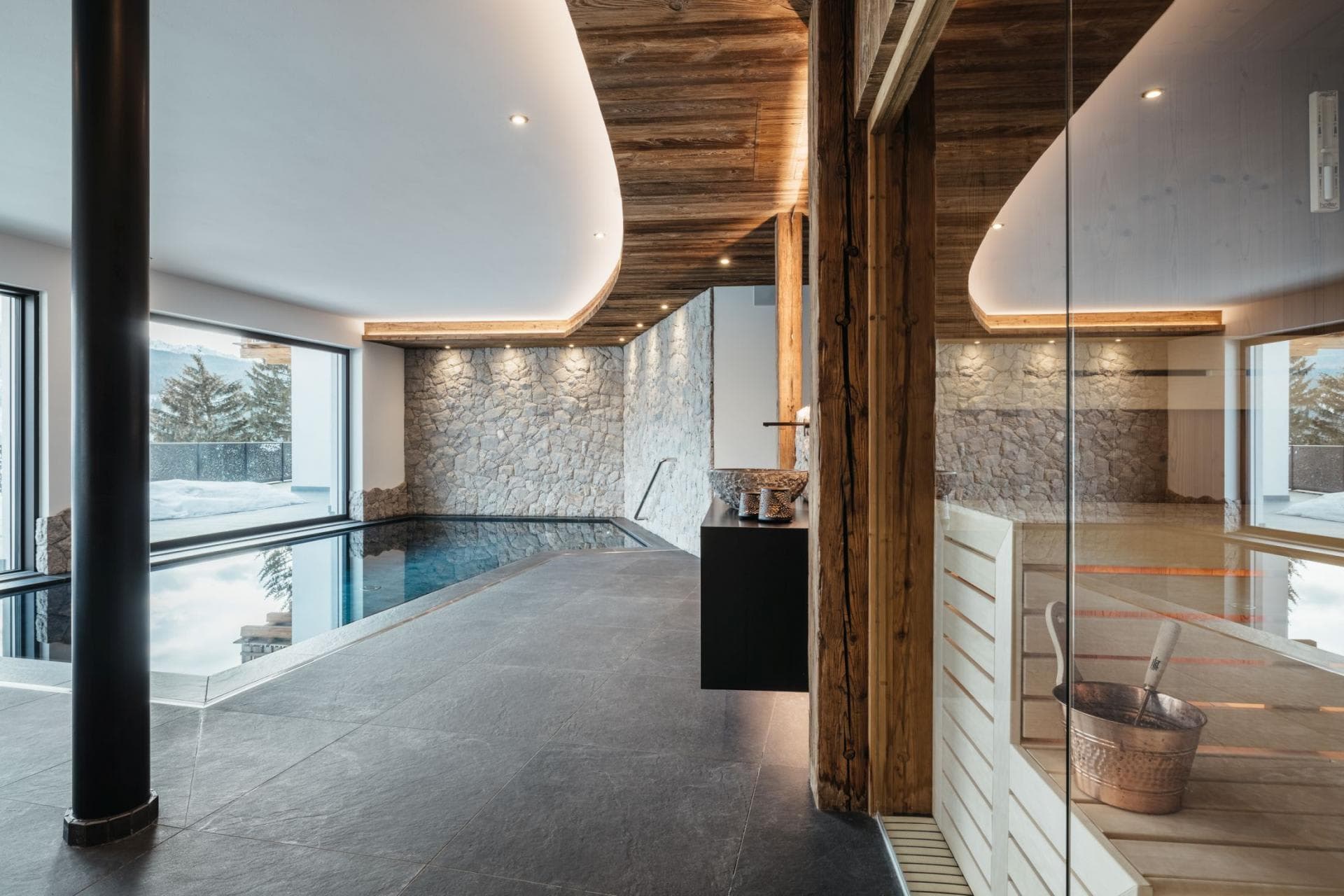Indoor pool and sauna with stone feature walls and mountain views