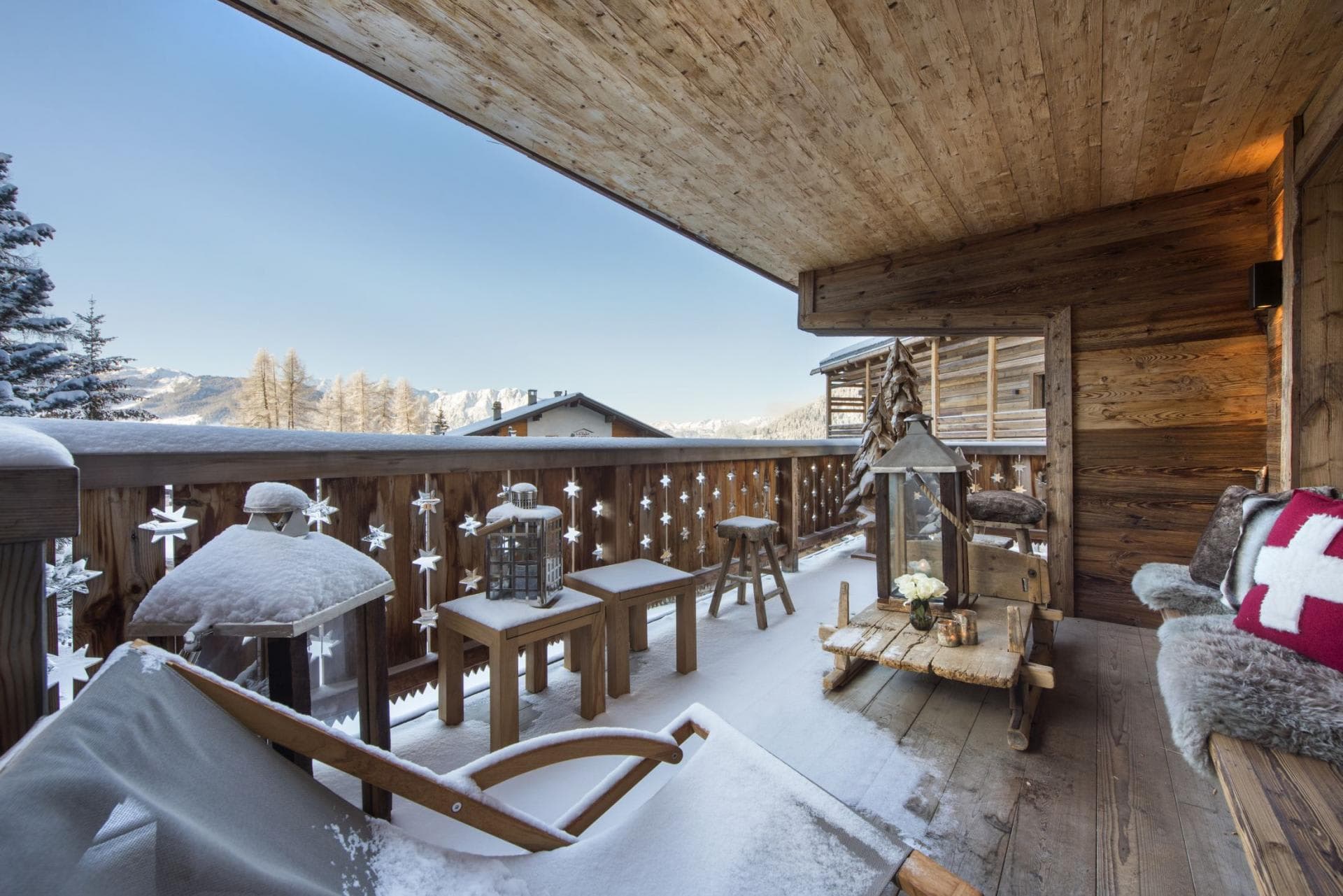 Covered balcony with mountain views, wood-slat railing, and fur-lined seating