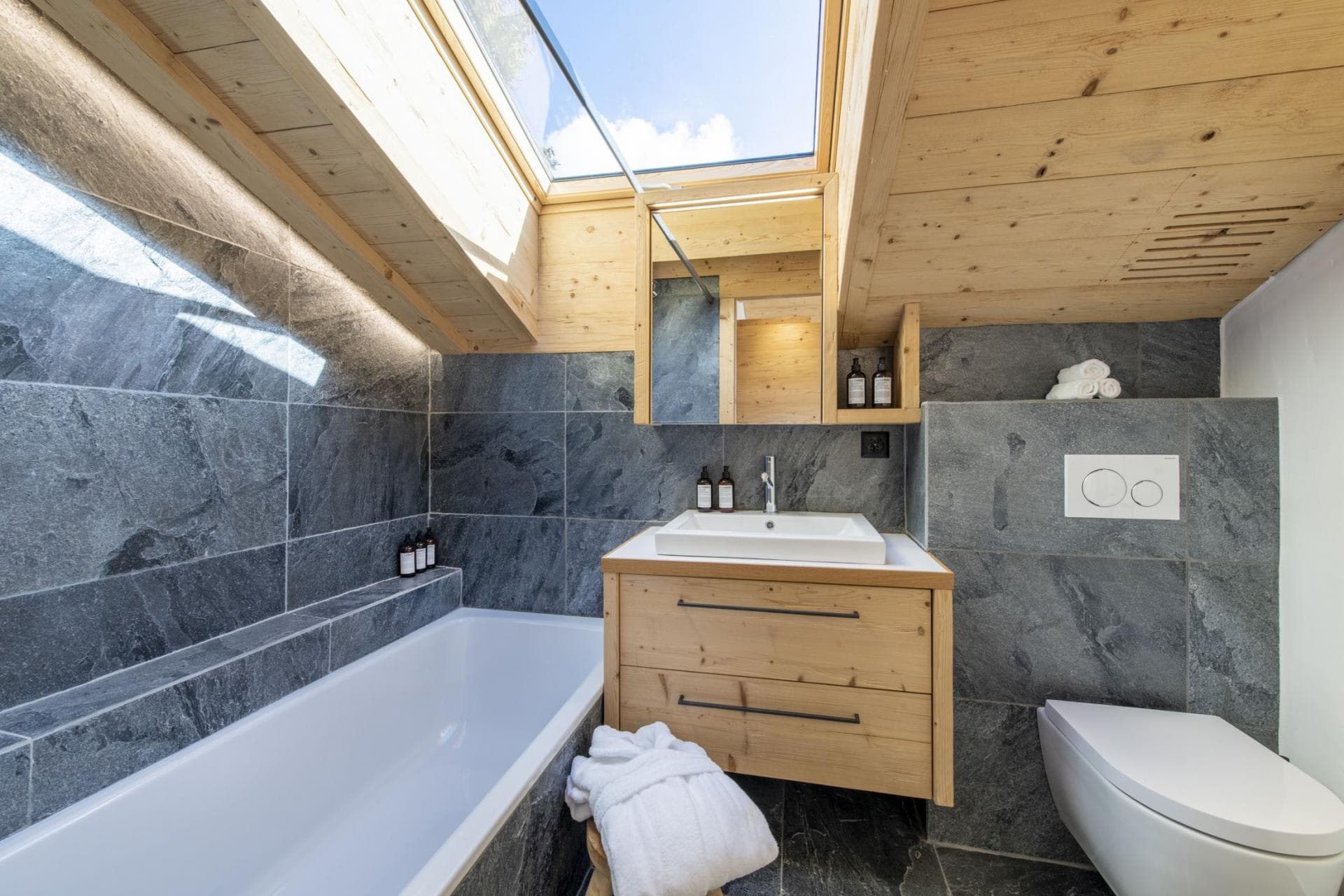 Bathroom with slate tile, soaking tub, and operable skylight