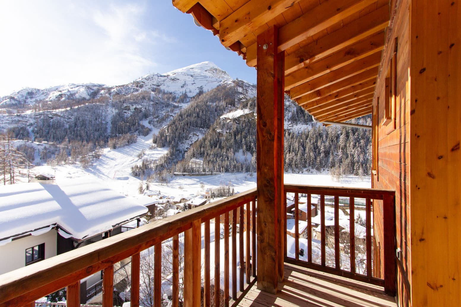 Covered wooden balcony with views of snow-capped mountains and village